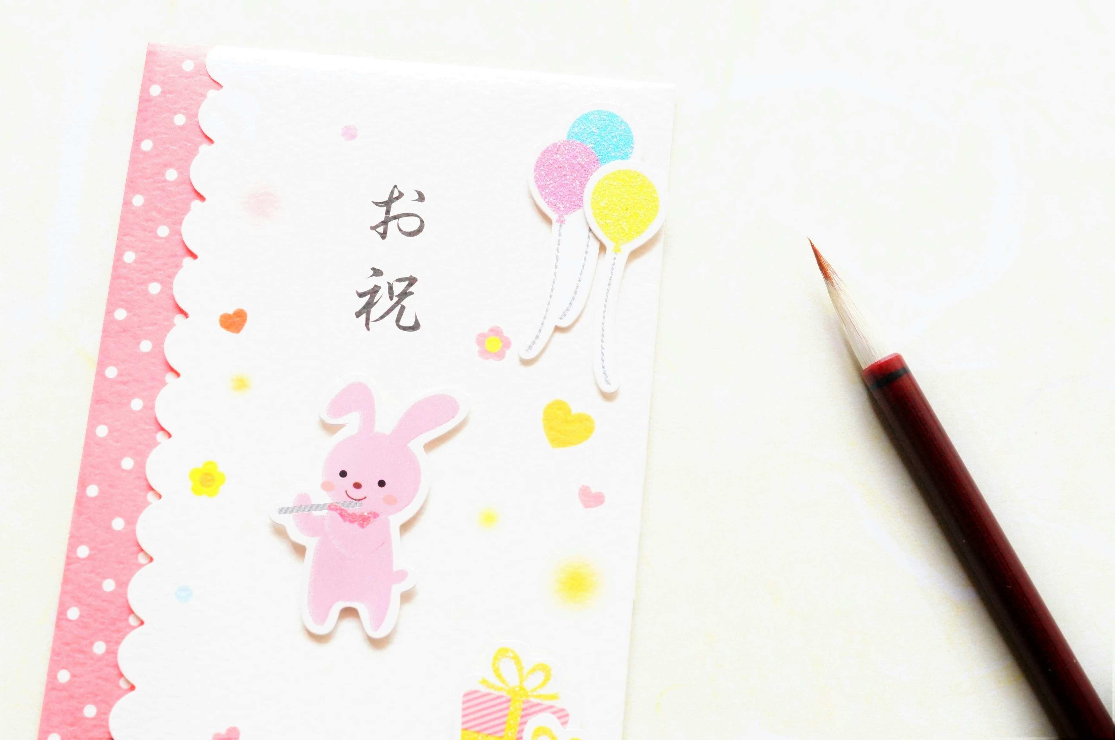 A celebration card featuring a pink rabbit illustration and colorful balloons