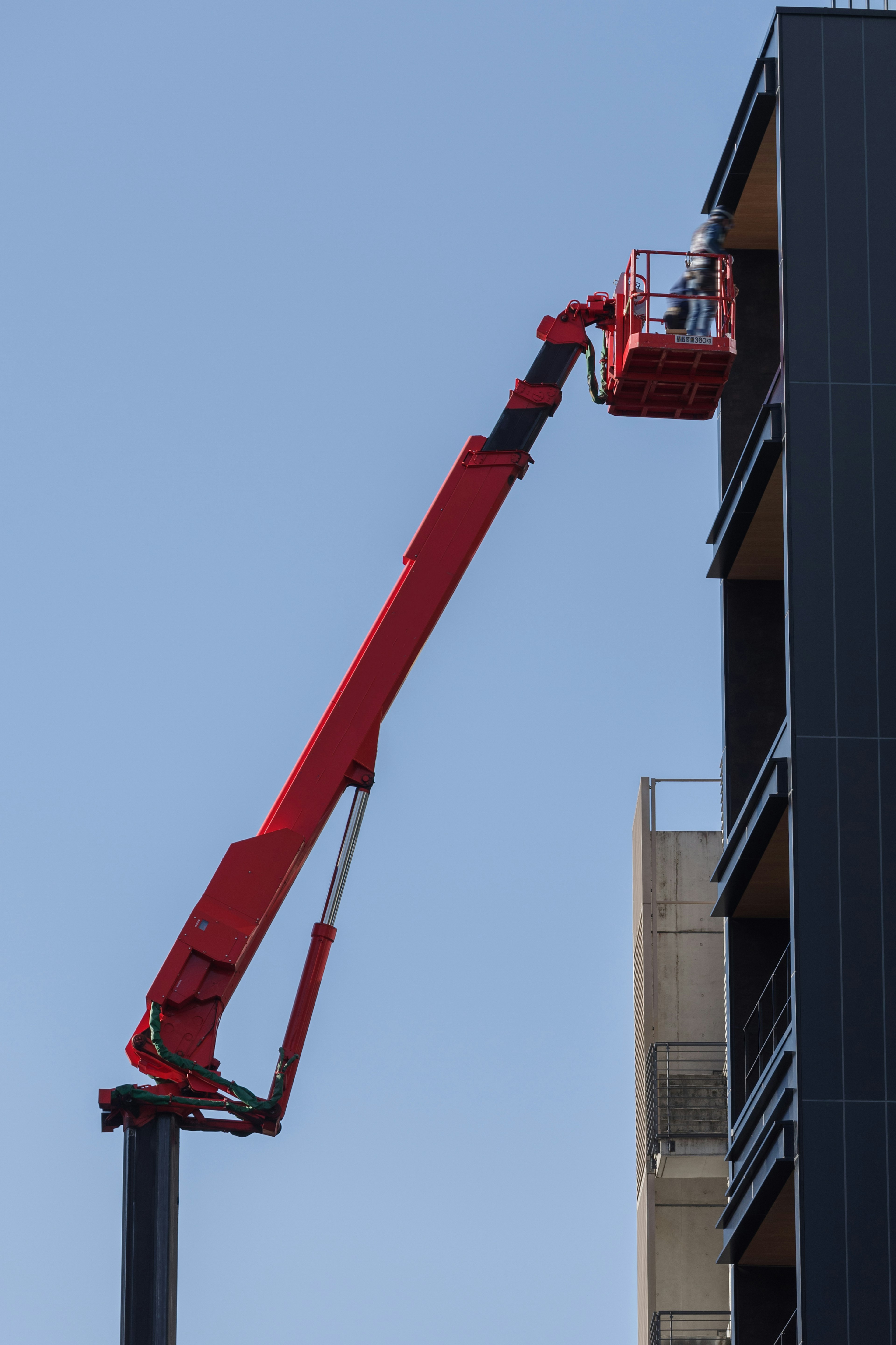 赤いクレーンが高層ビルの窓を作業している