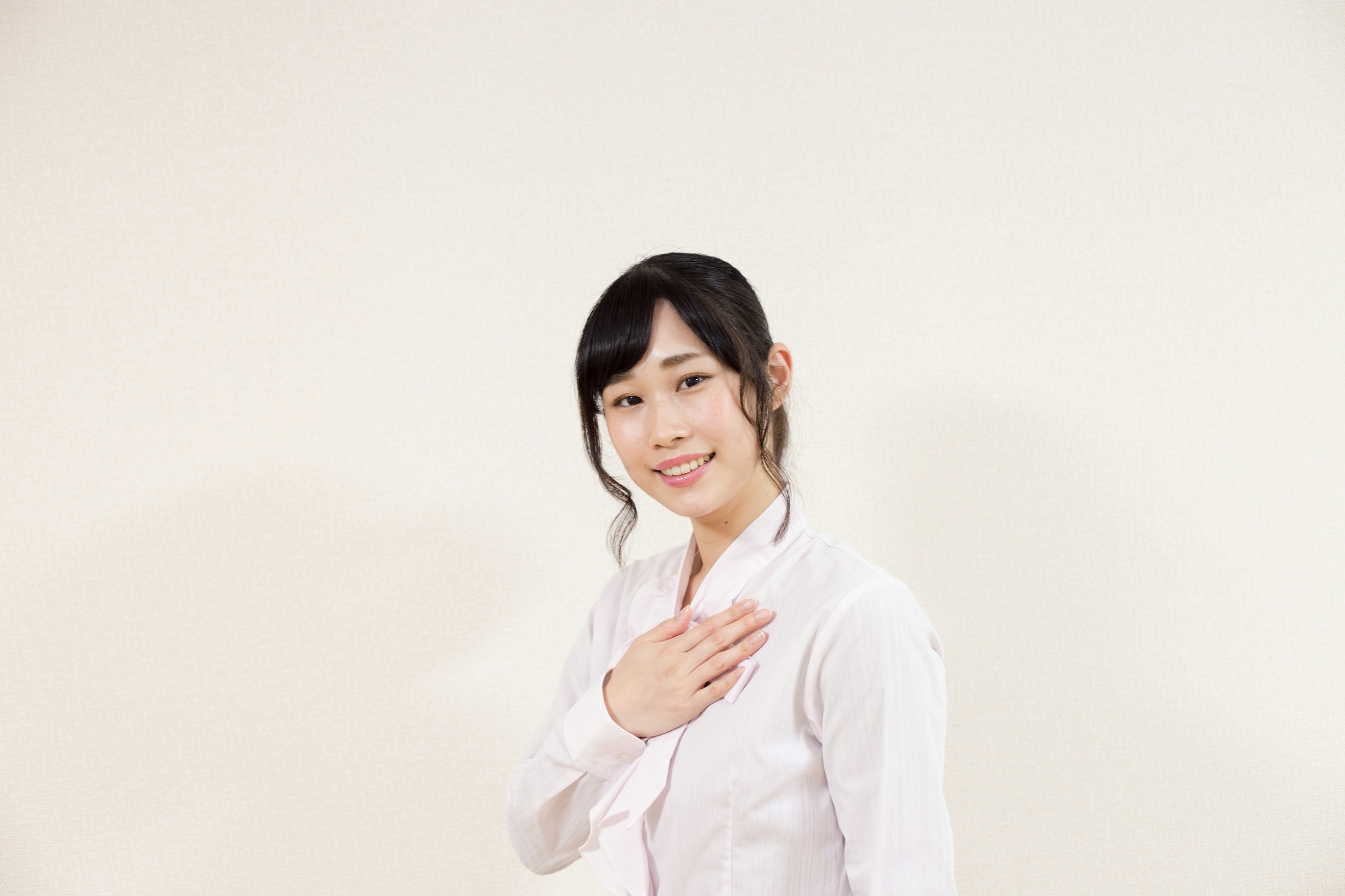 A woman in a white shirt smiling with her hand on her chest