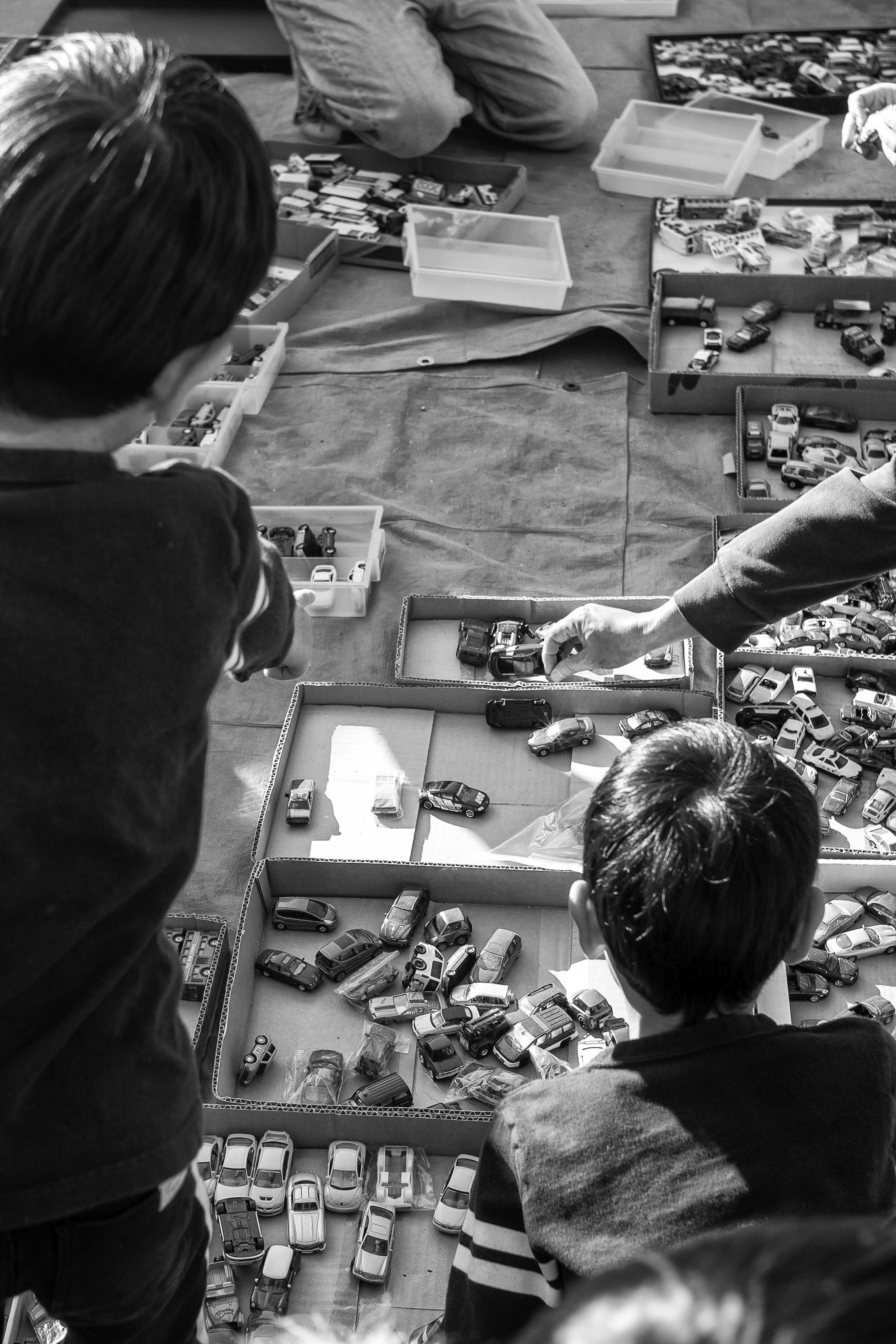 Schwarzweißfoto von Kindern, die Spielzeugautos auswählen