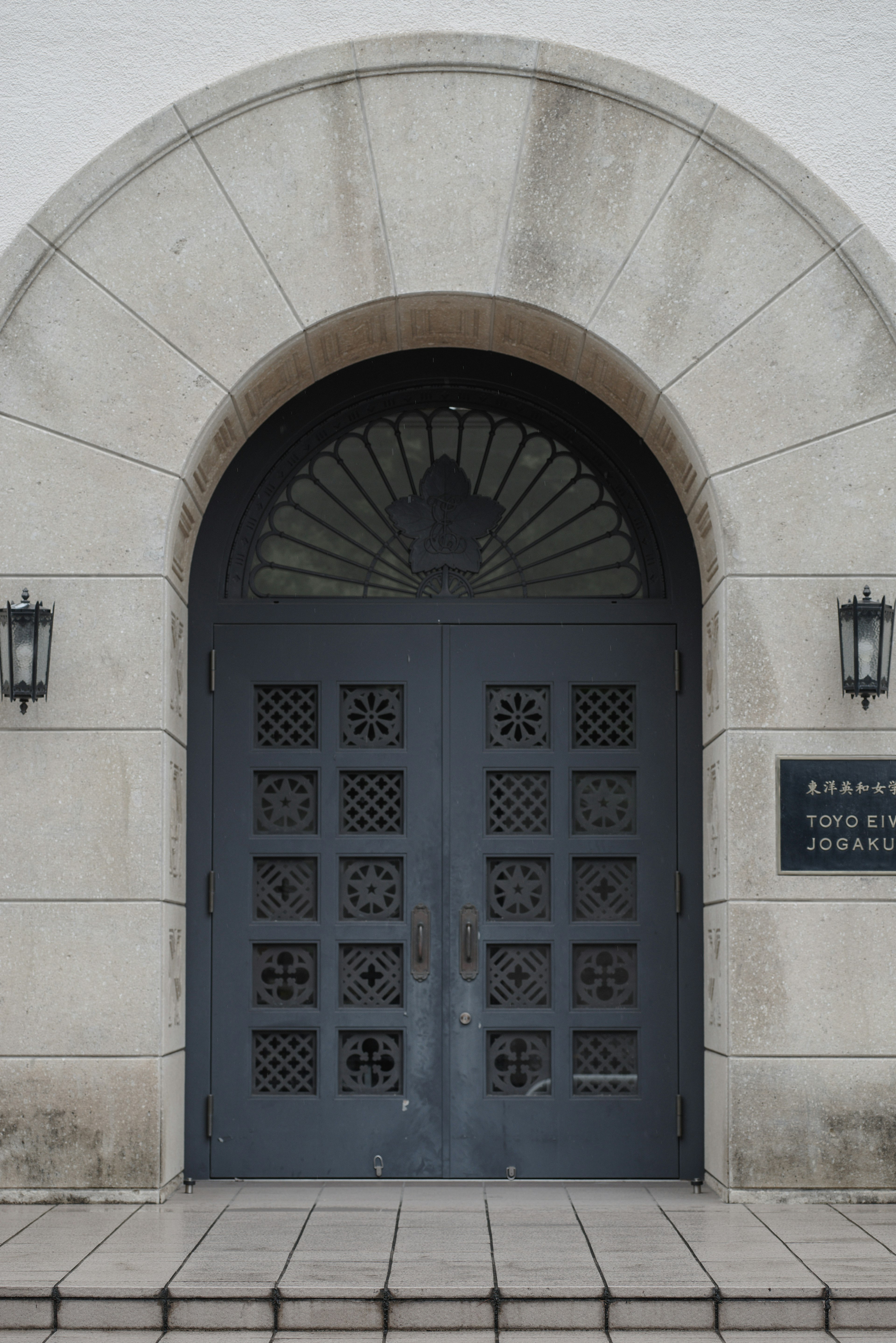 Arched gray door with decorative windows at building entrance