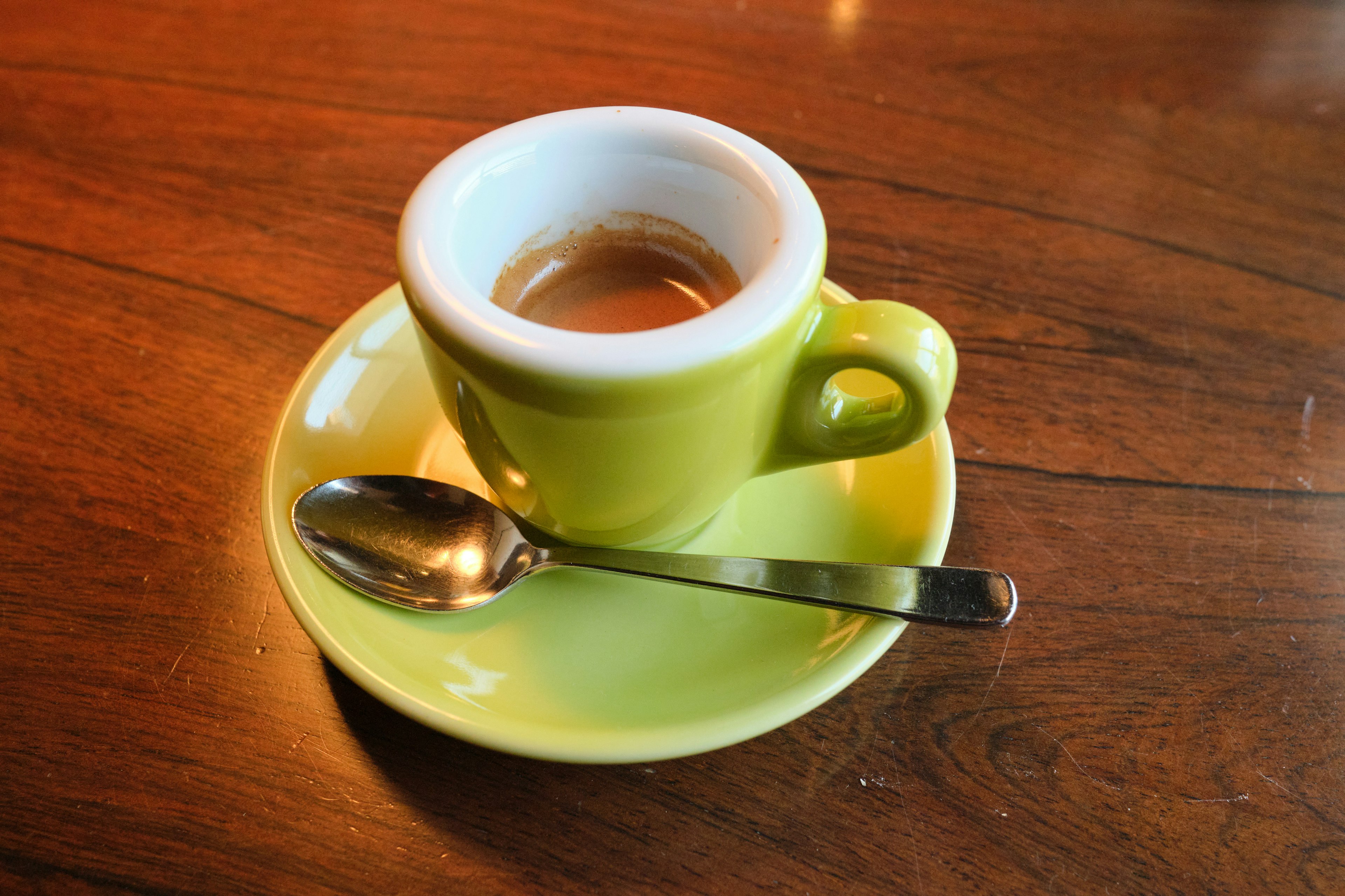 Espresso in a green cup with a silver spoon