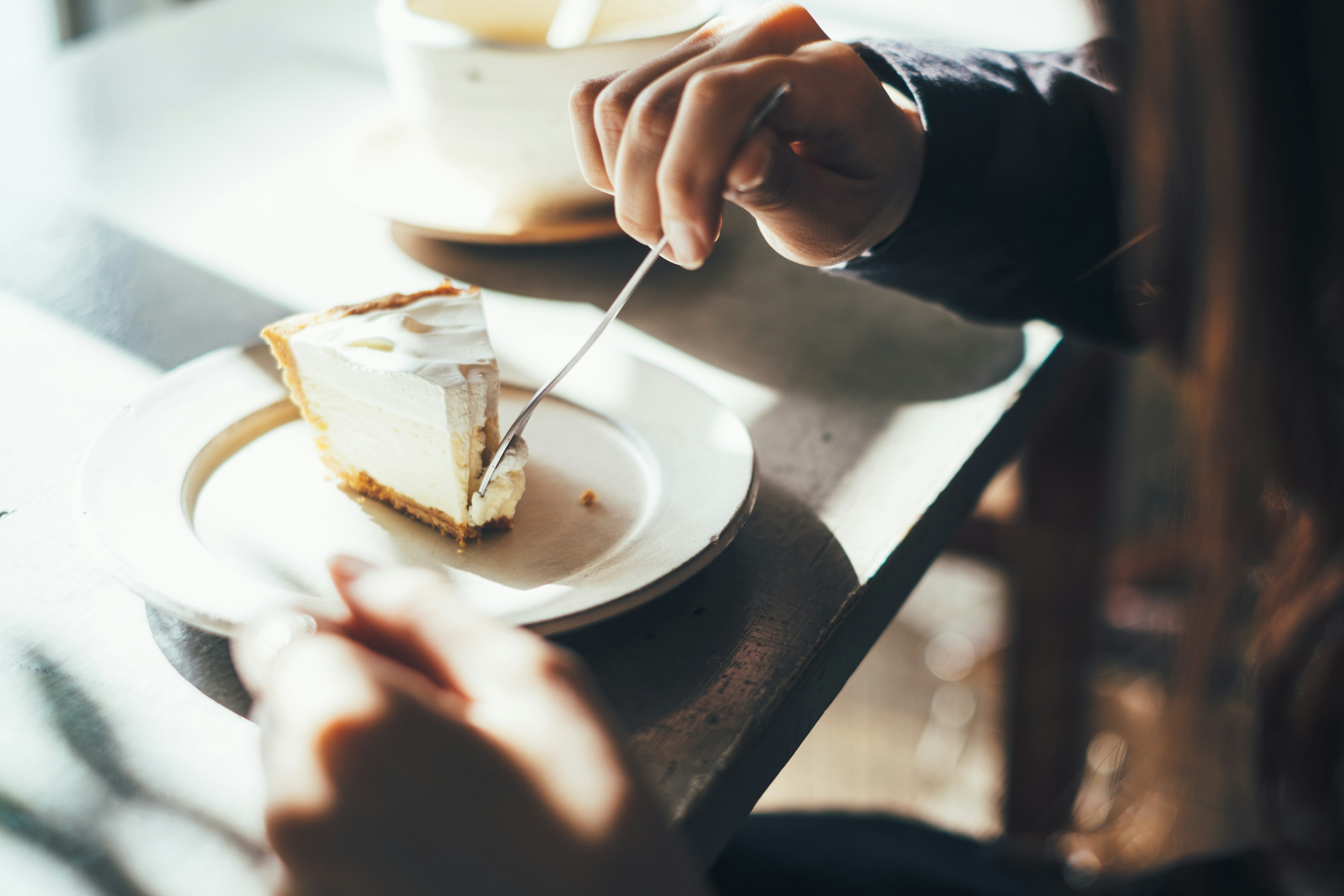 Kedekatan tangan menikmati sepotong cheesecake di meja