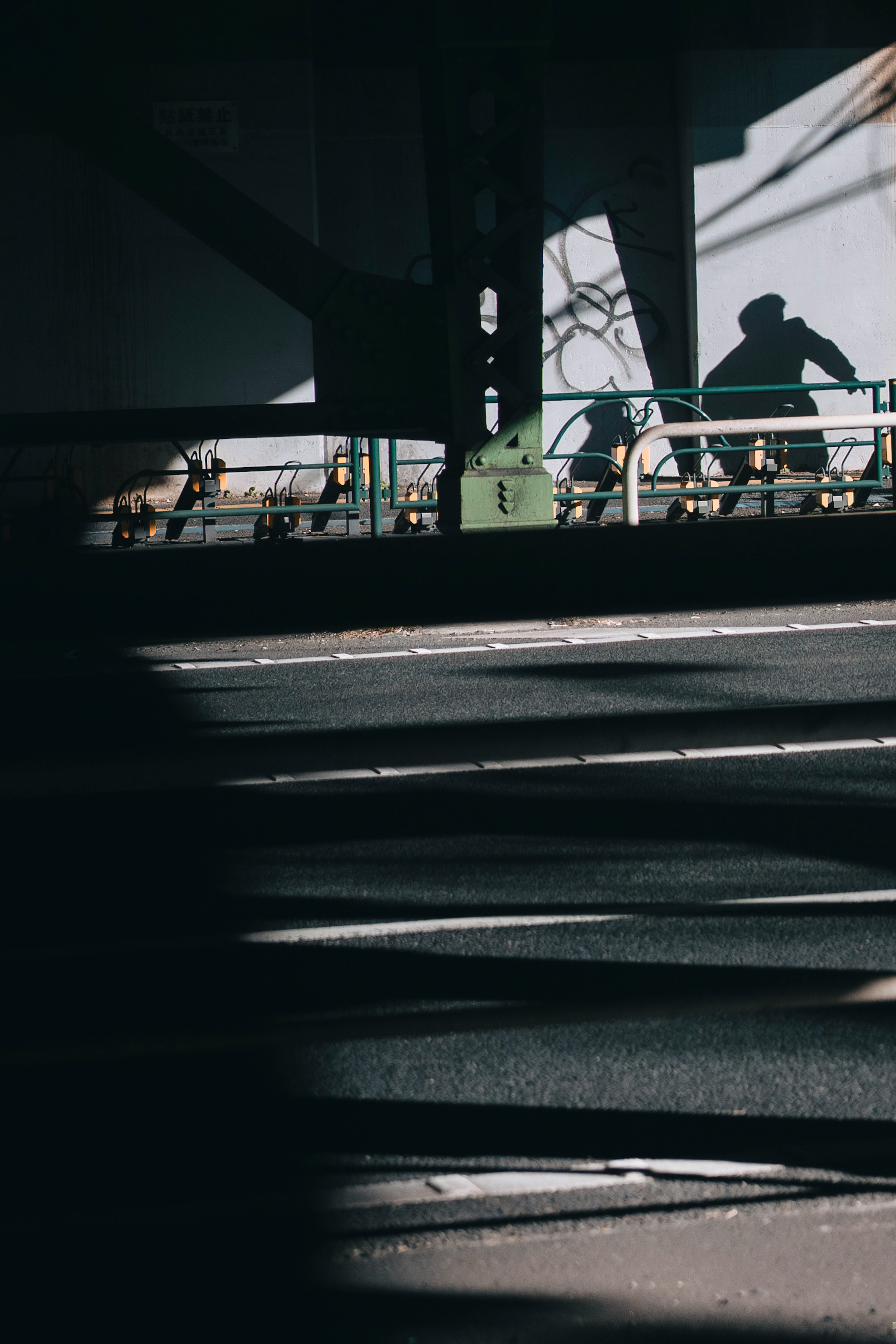 Shadows on stairs with a figure silhouetted under a bridge