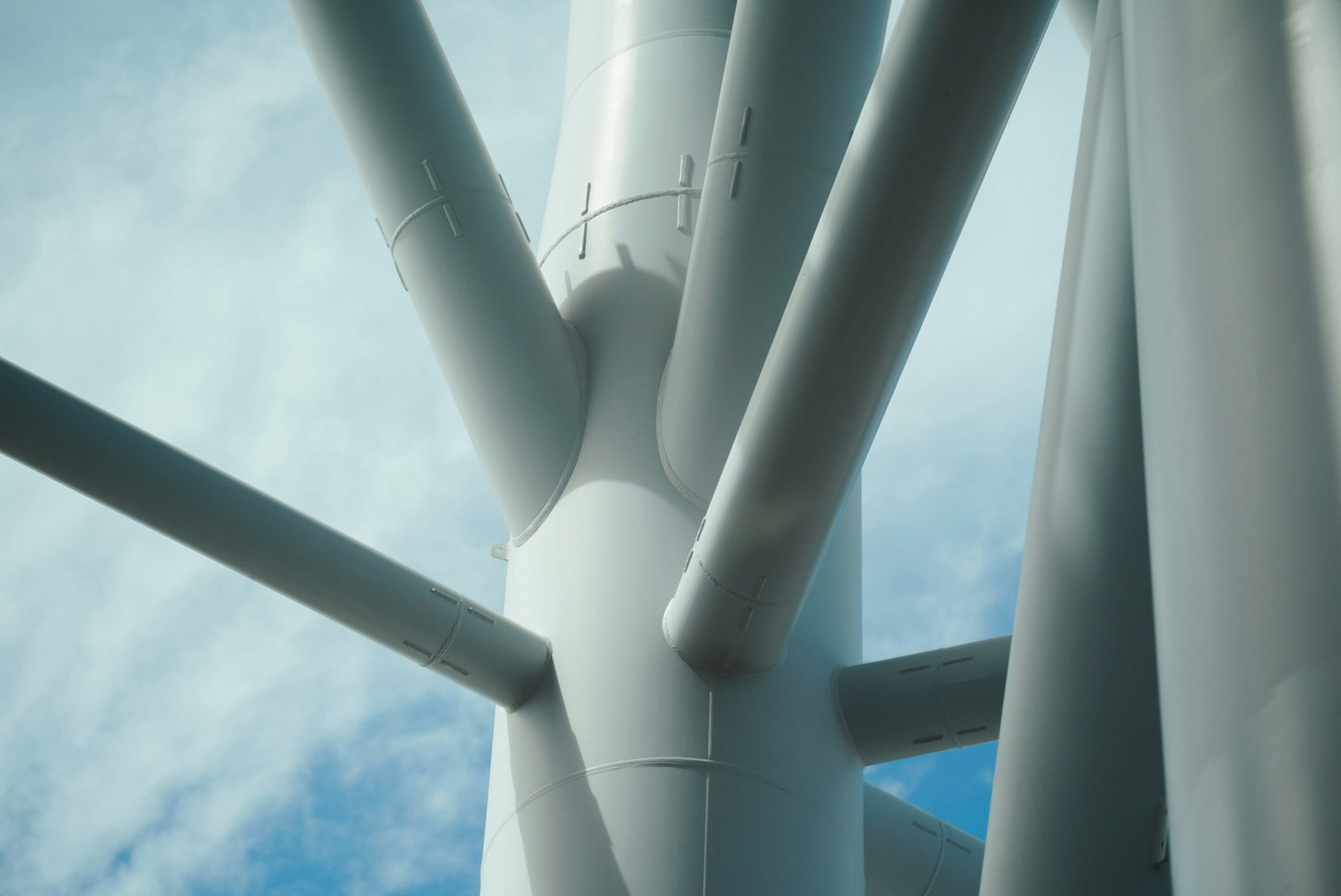 Immagine ravvicinata della struttura di una turbina eolica con tubi e cielo blu