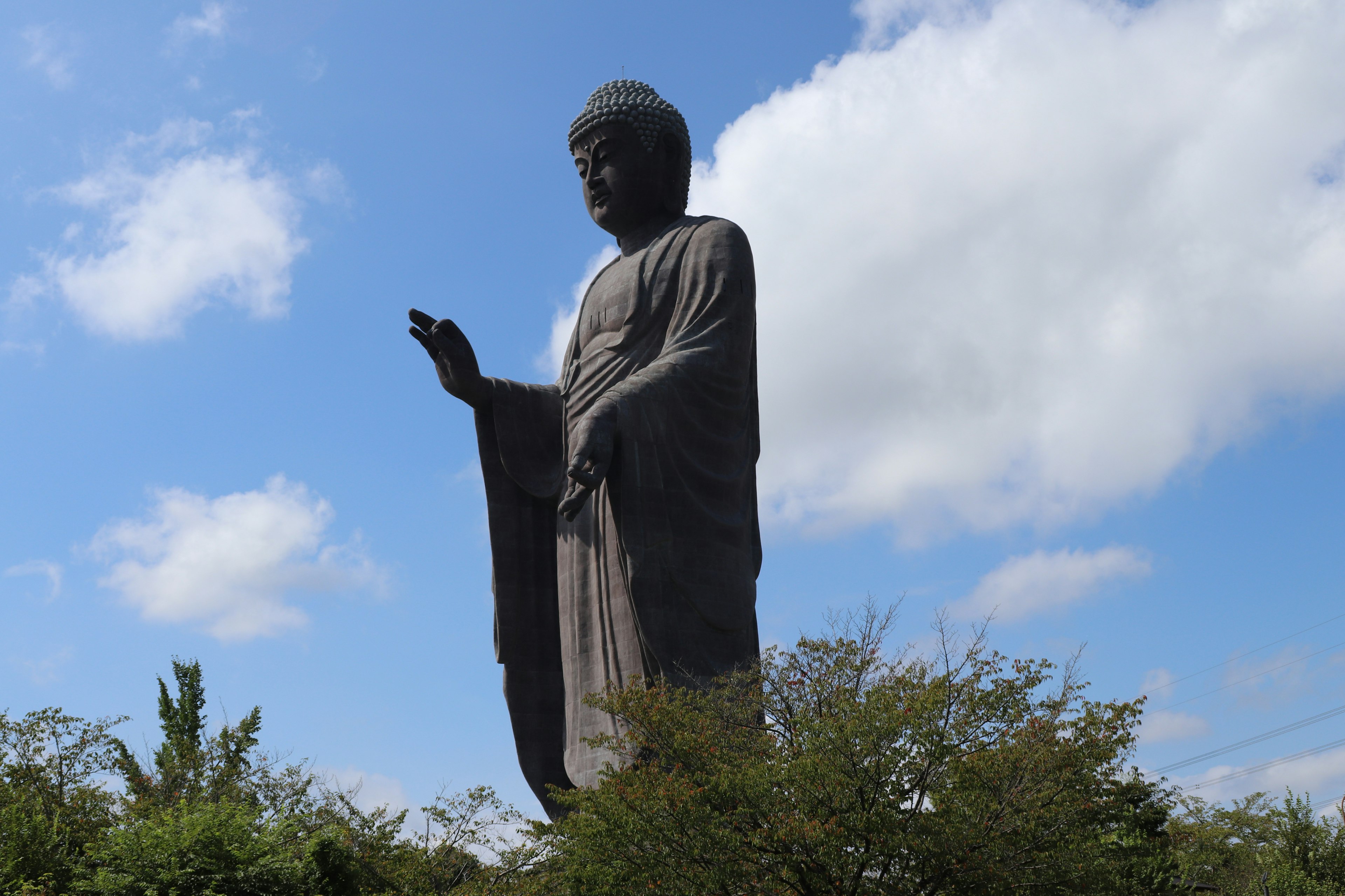 Große Buddha-Statue mit erhobener Hand vor blauem Himmel