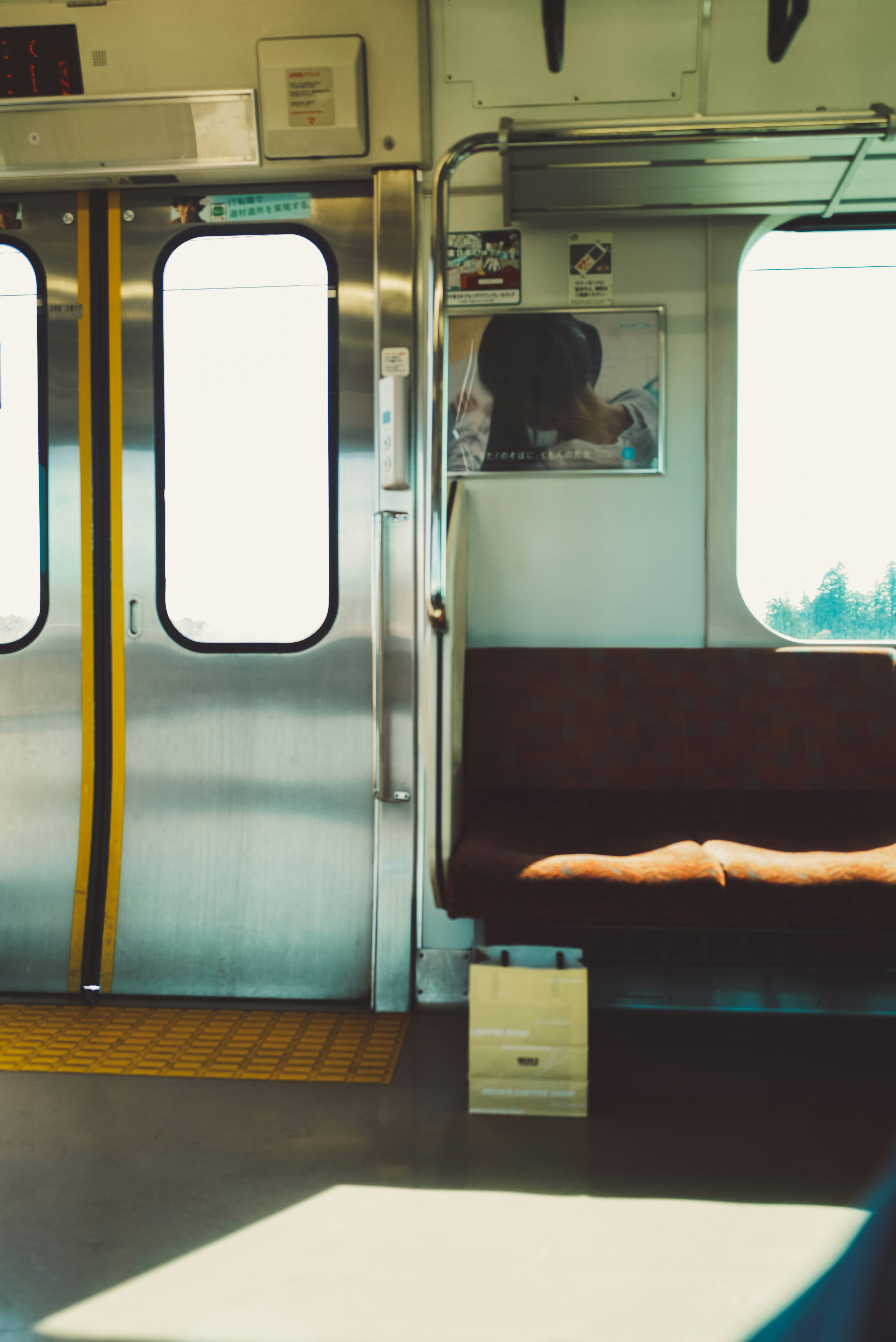 Interior de un tren que muestra un asiento vacío y un área cerca de la puerta