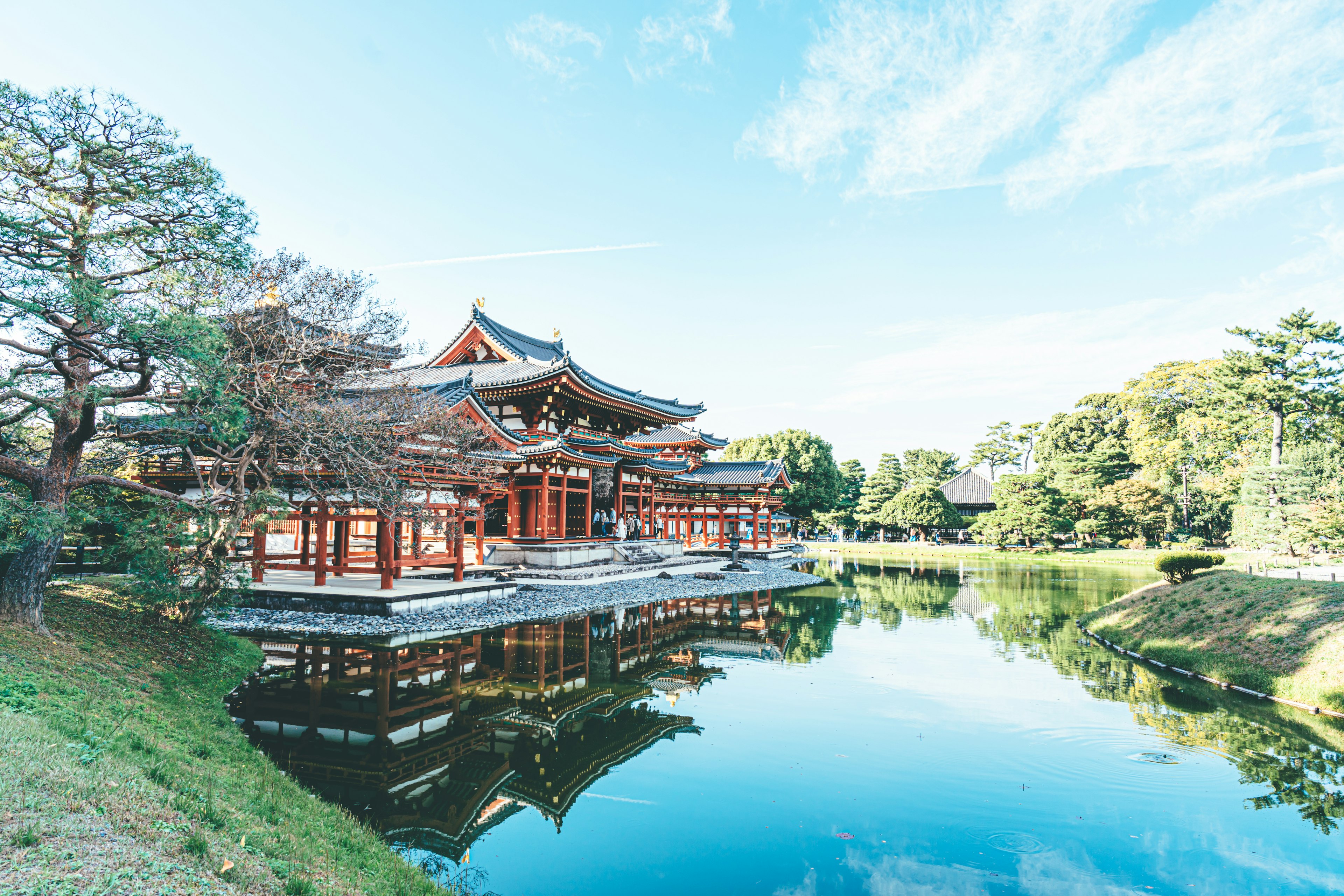 Traditional Japanese building by a serene pond surrounded by trees