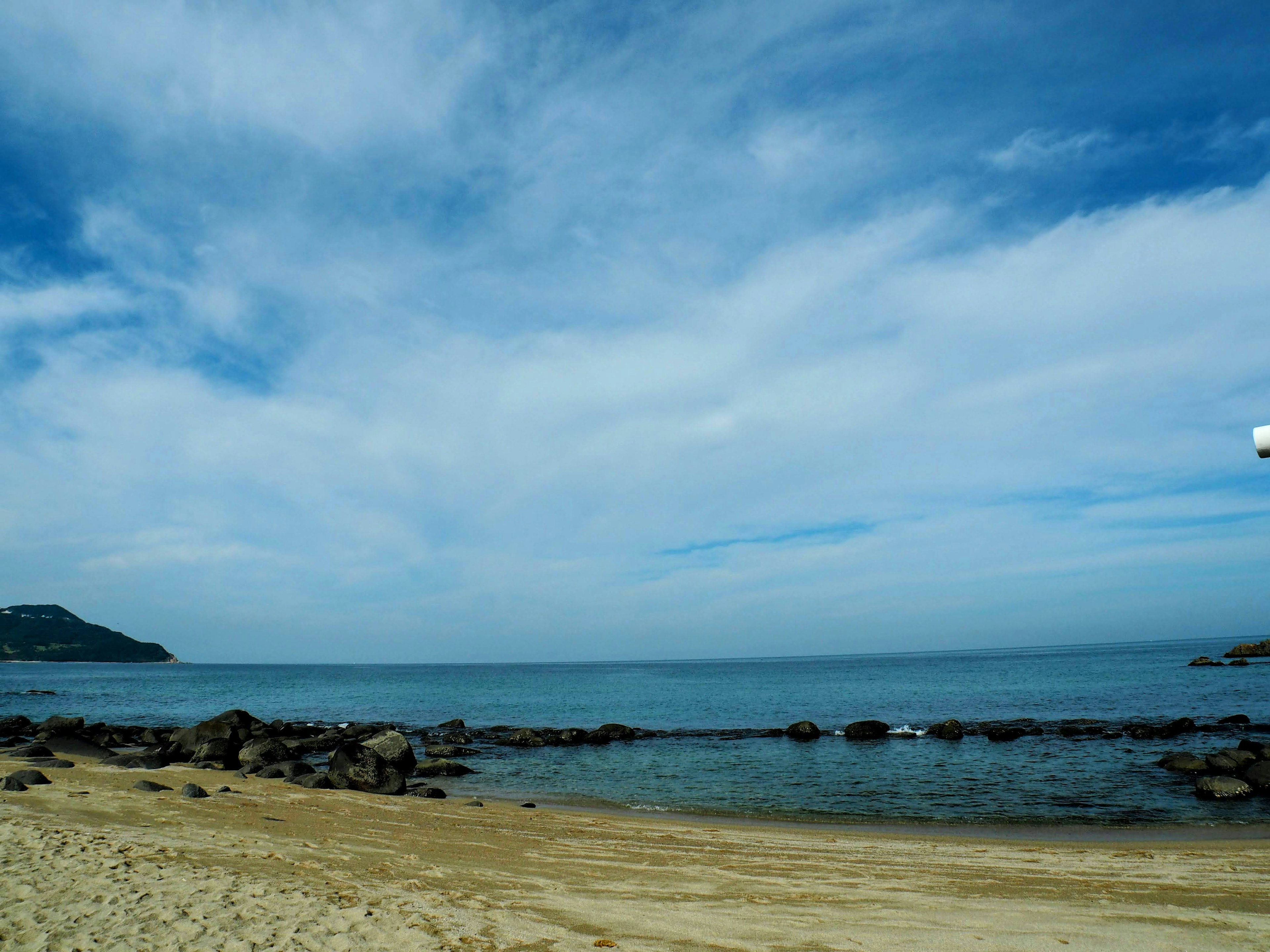 ชายหาดเงียบสงบกับมหาสมุทรสีน้ำเงินและท้องฟ้าที่สงบ