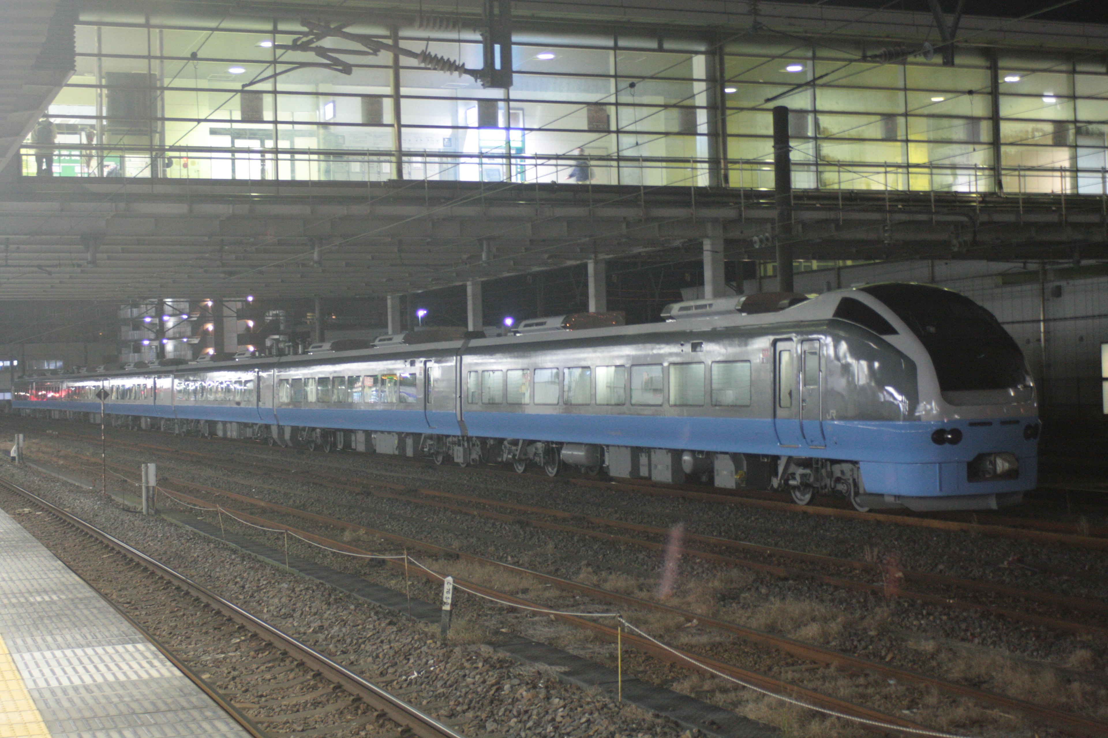 Blue train parked at a station during the night