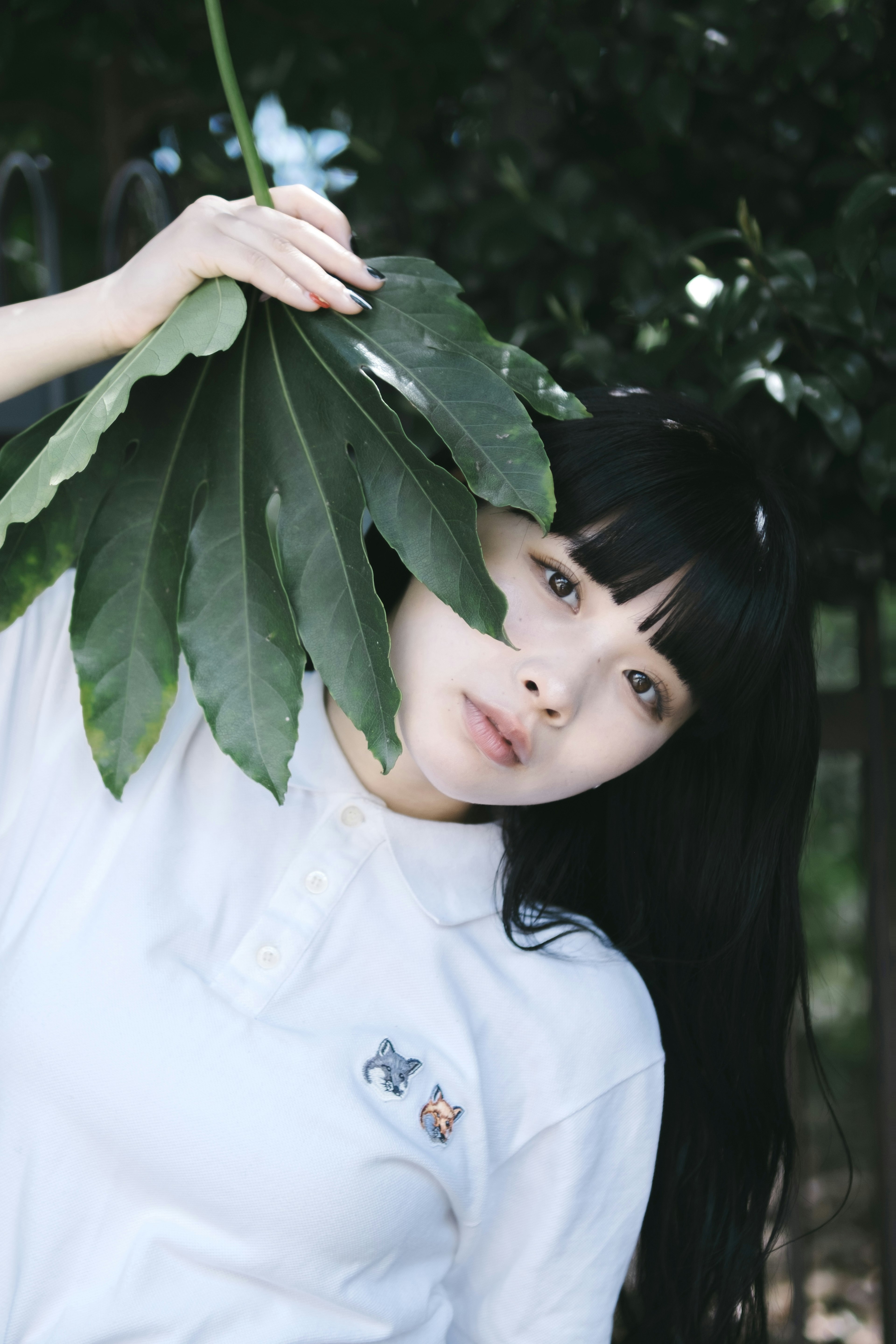 A woman holding a large leaf in a natural setting