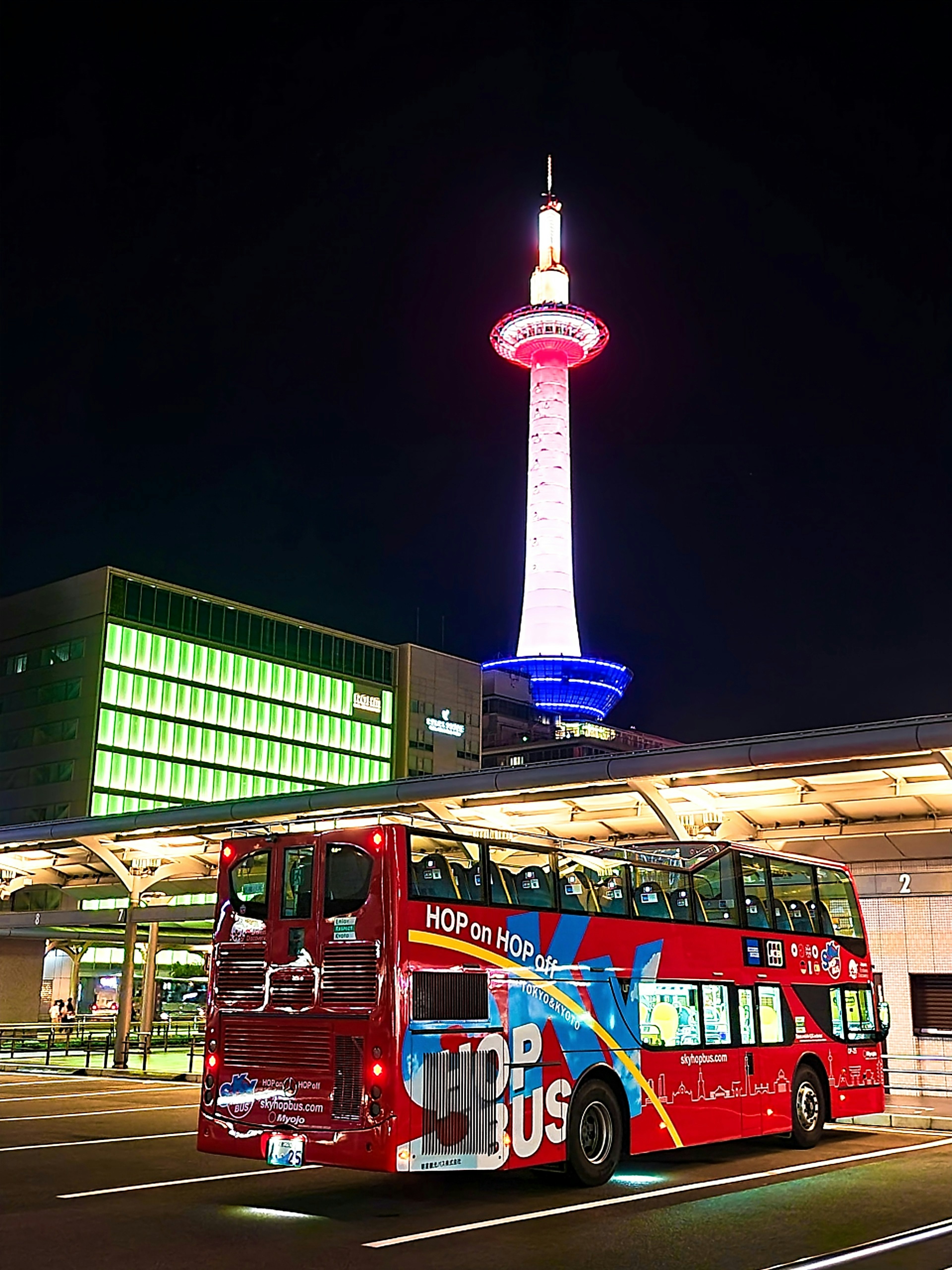 Nachtansicht des Kyoto Towers mit einem roten Sightseeing-Bus