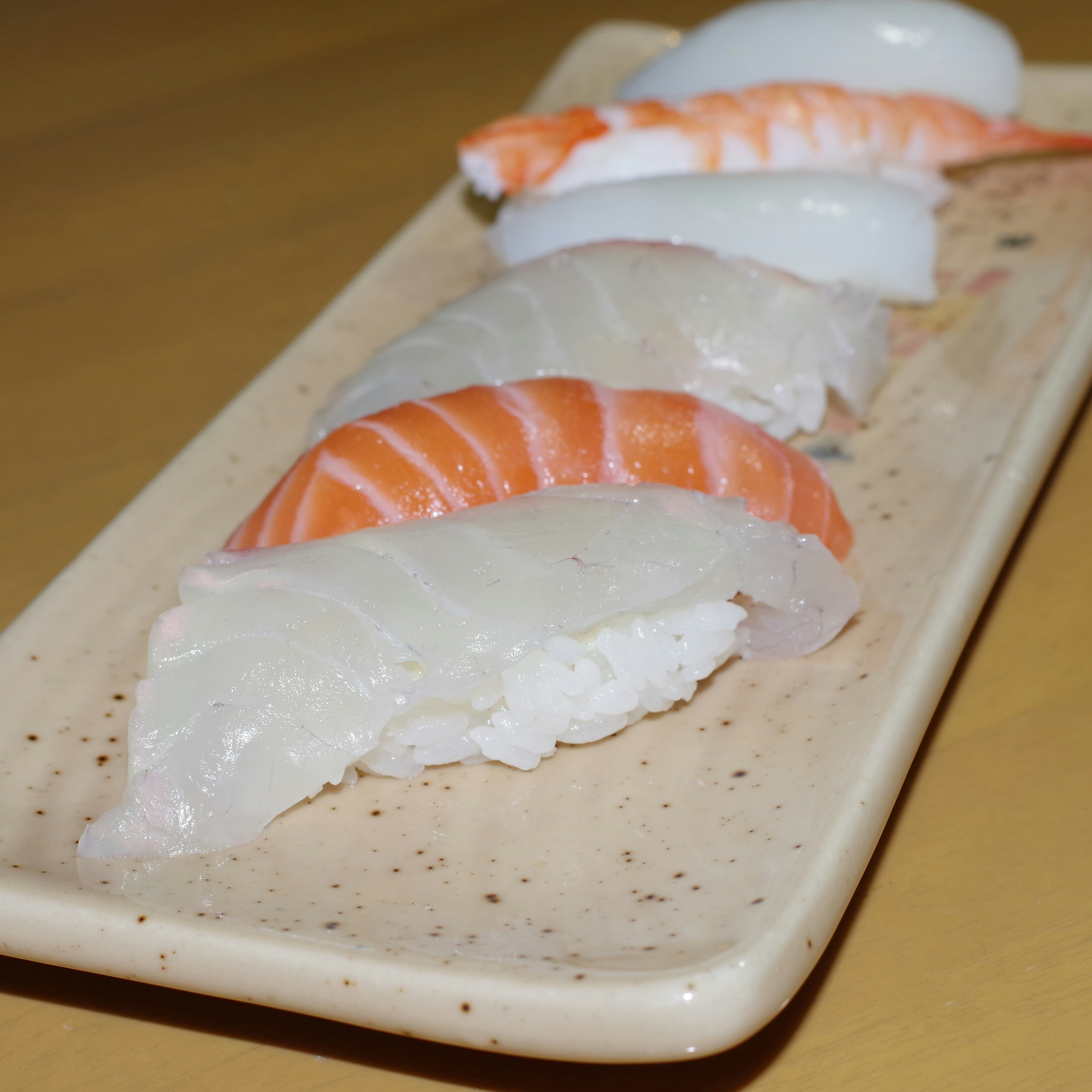 Piring sushi salmon yang cerah disusun dengan indah