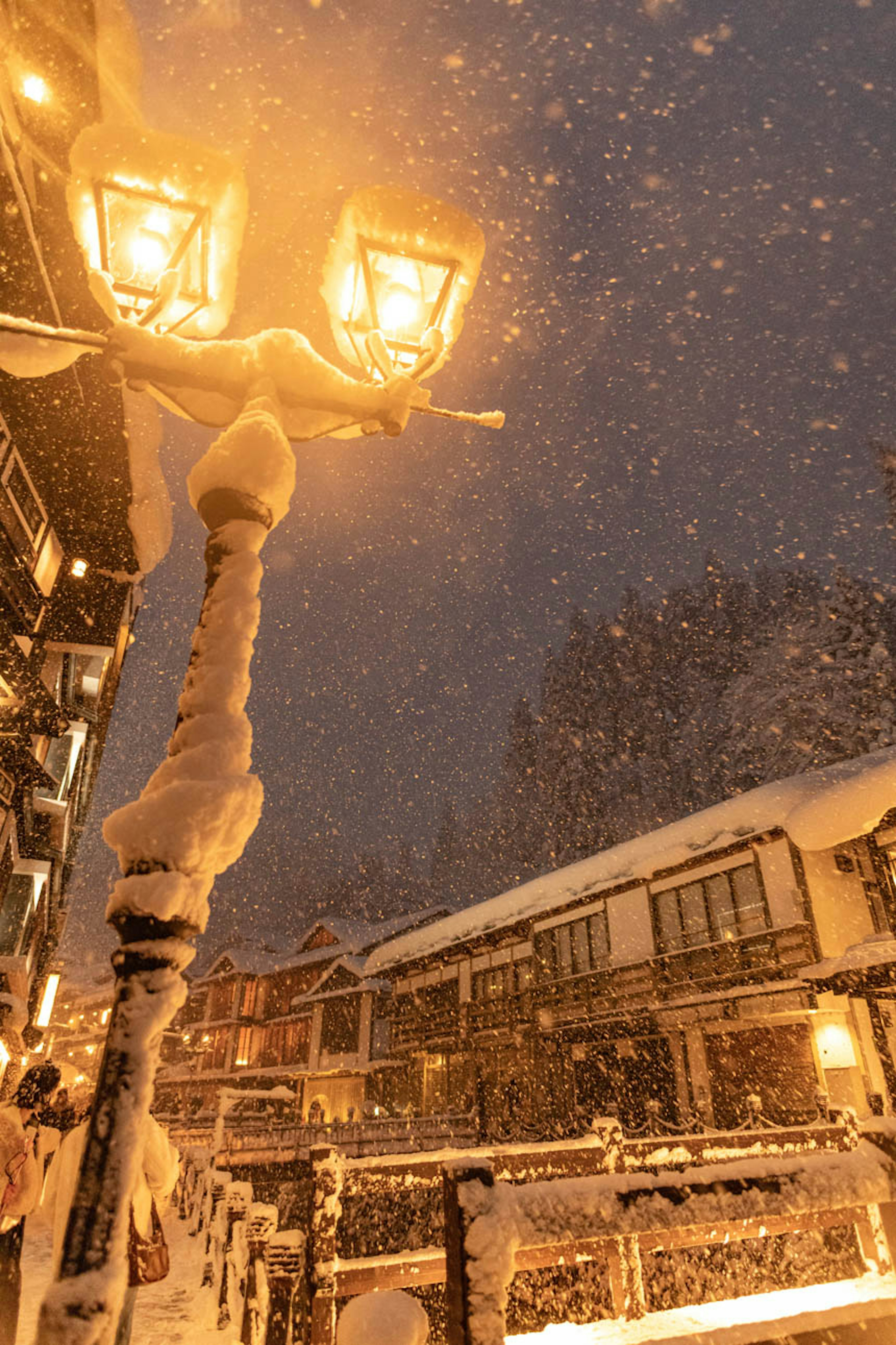 Eine verschneite Nachtszene mit beleuchteten Straßenlaternen und schneebedeckten Gebäuden