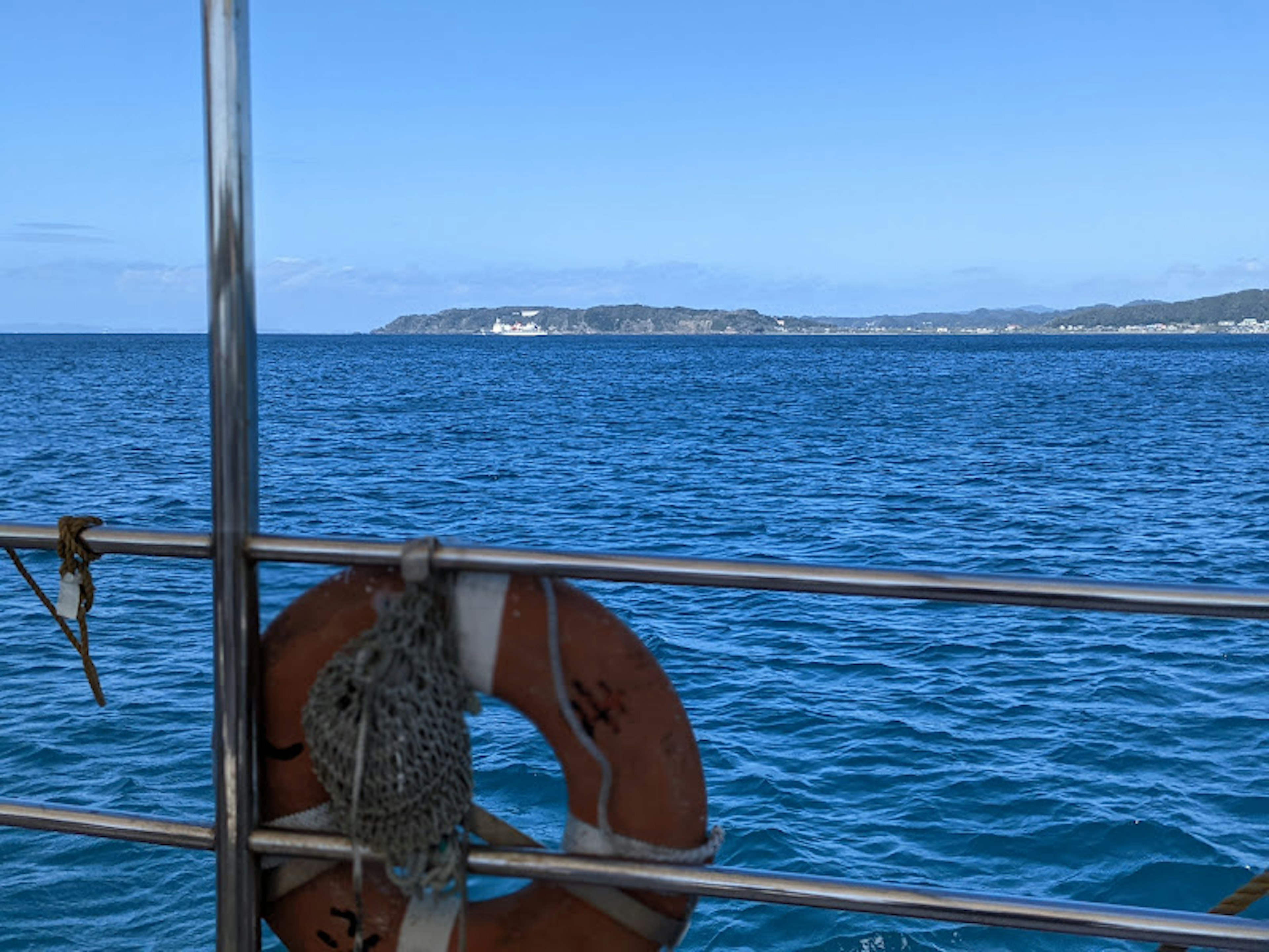 Lifebuoy in the foreground with a blue sea and distant coastline