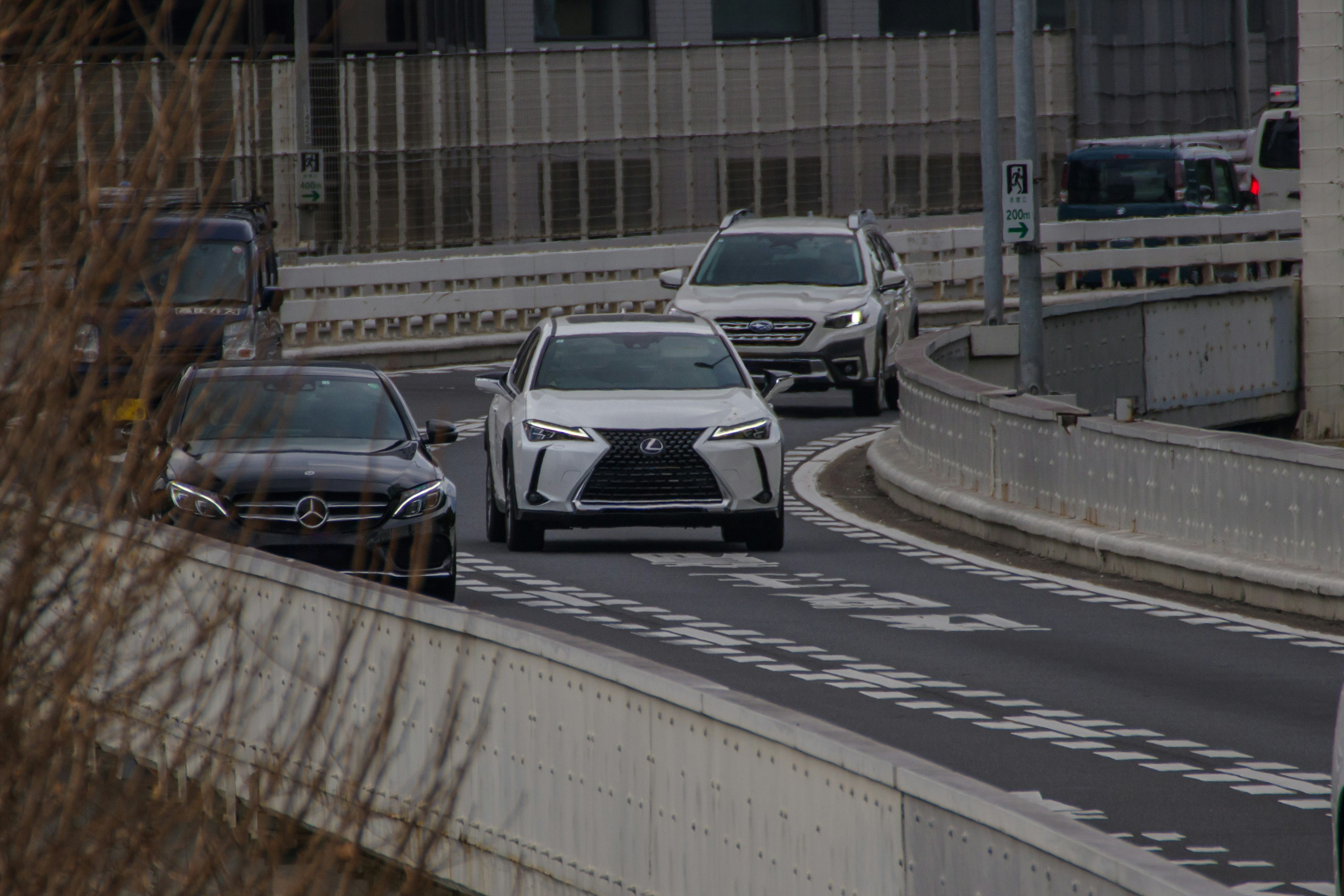 Cars driving in the city featuring a white SUV and a black sedan