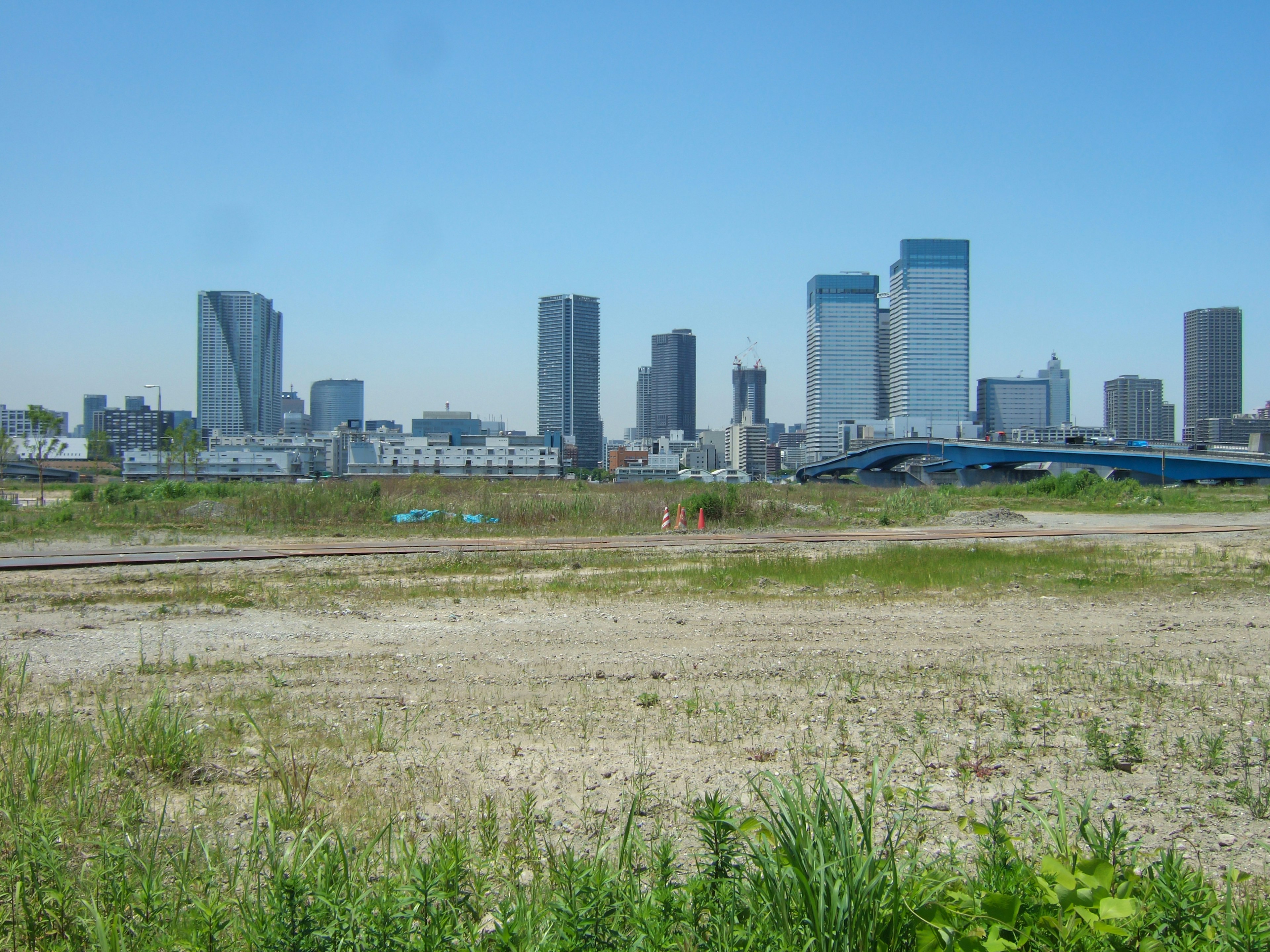 Urban skyline under blue sky with grassy foreground