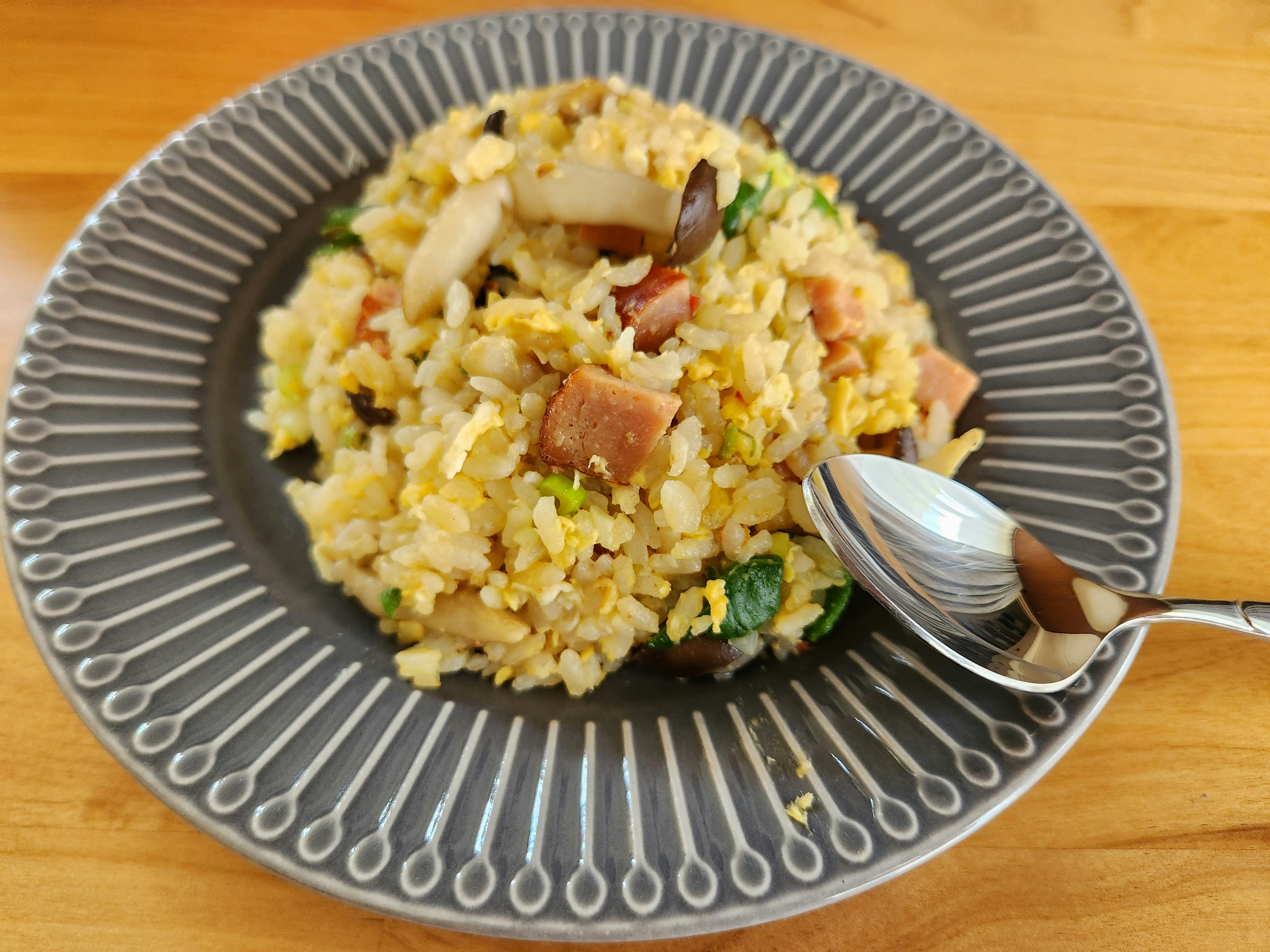 맛있는 볶음밥이 회색 접시에 담겨 있고 숟가락이 있습니다