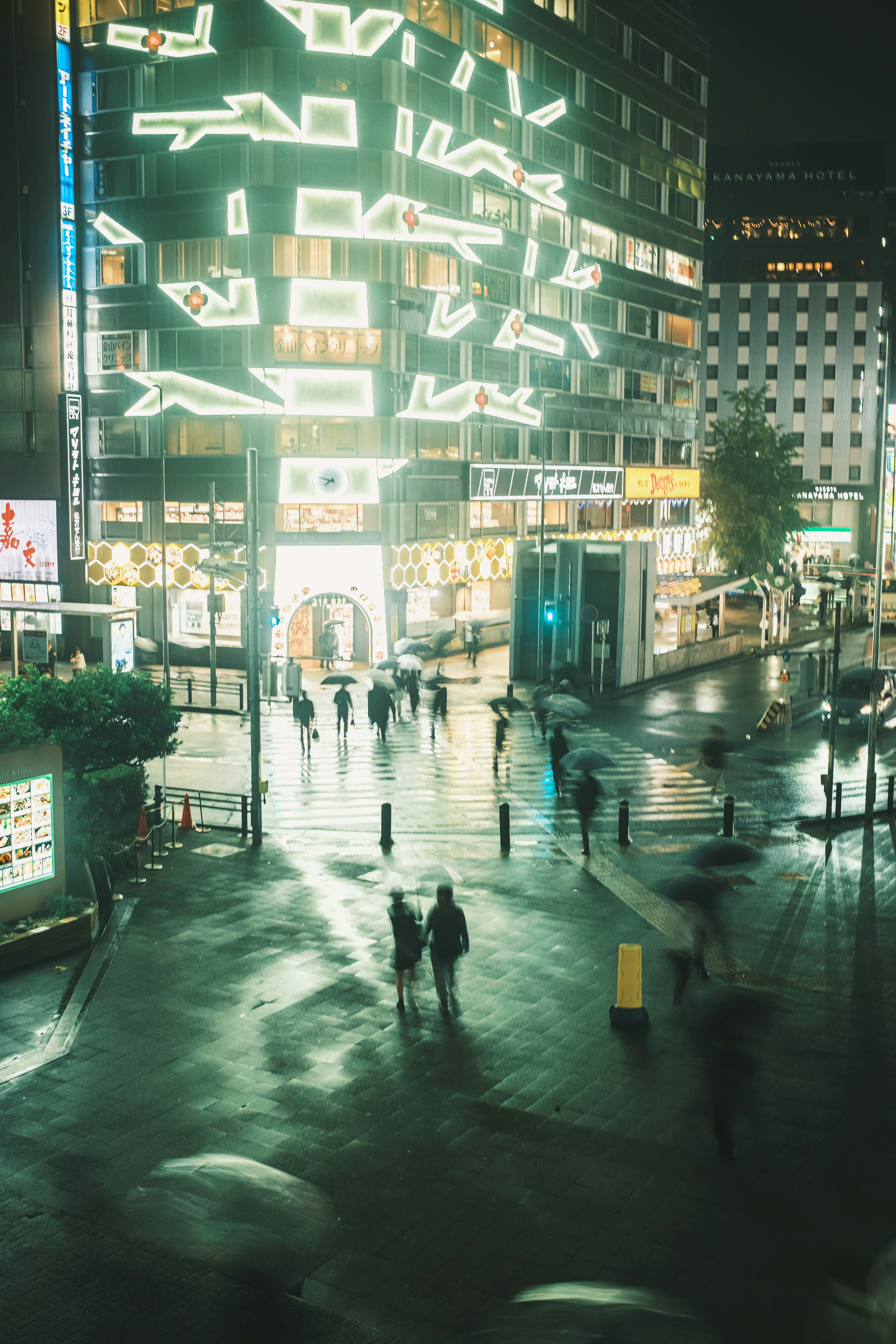 People walking on a city street at night with bright neon lights on buildings