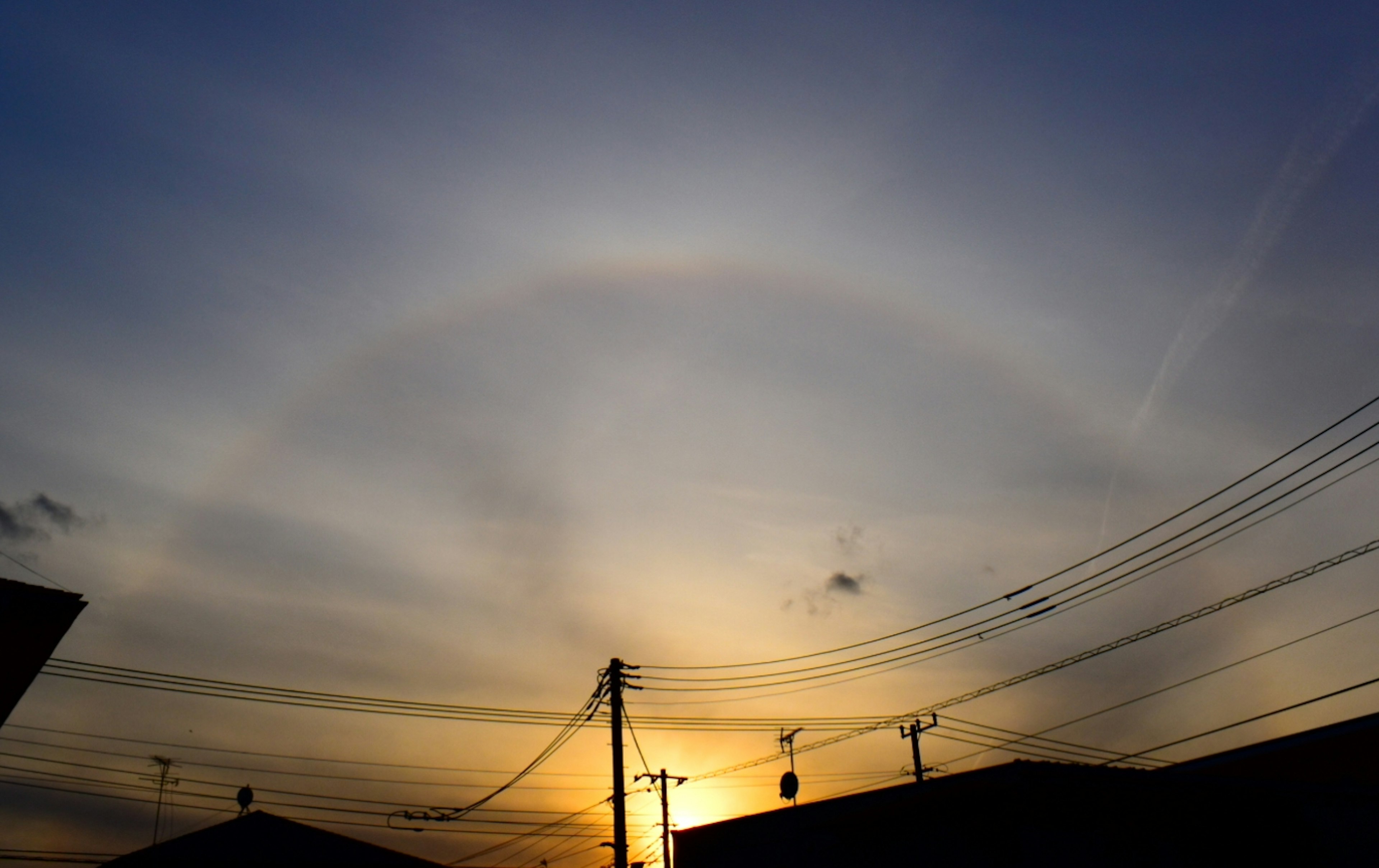 Halo circular arco iris alrededor de la puesta de sol con líneas eléctricas