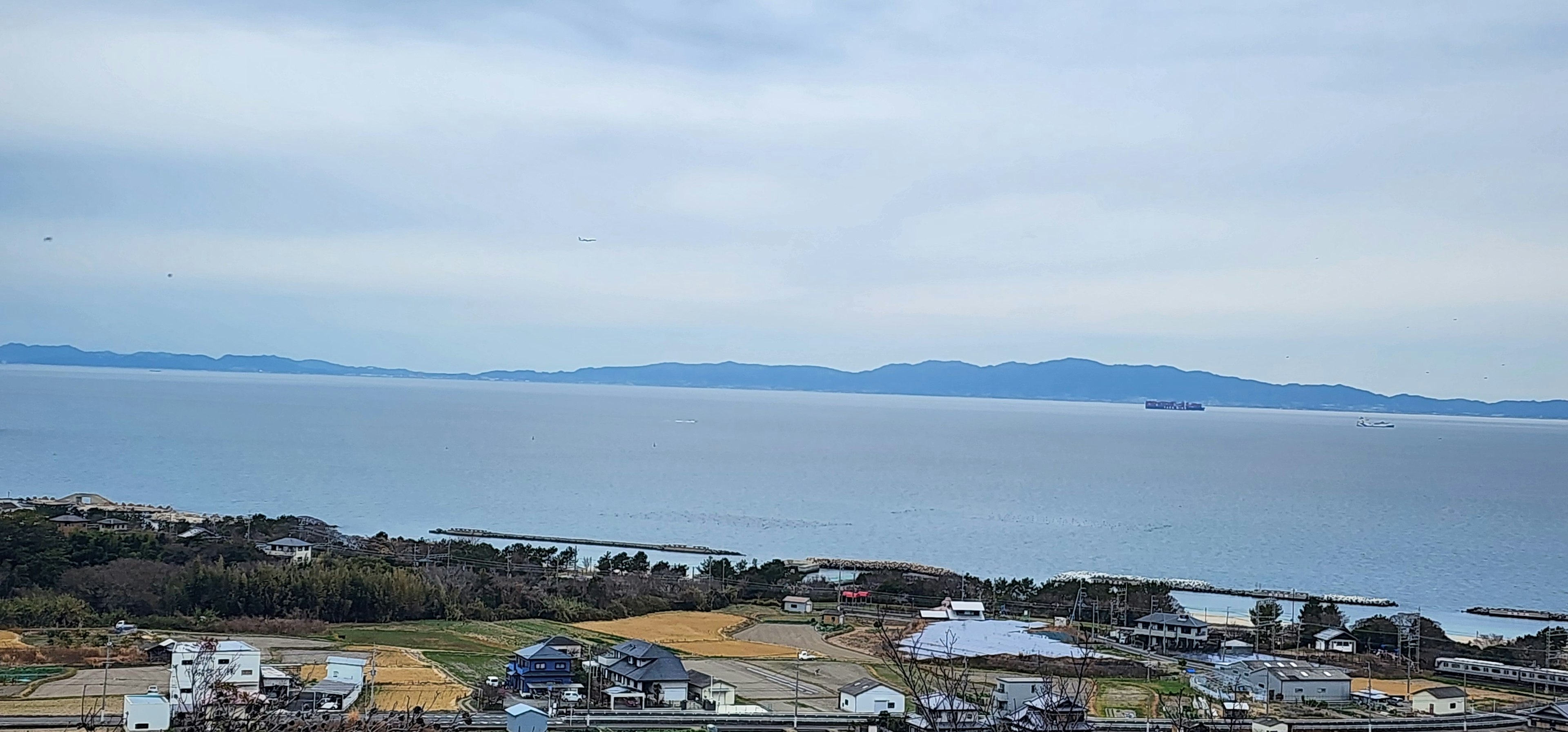 宁静的蓝色海洋和岛屿在柔和的多云天空下