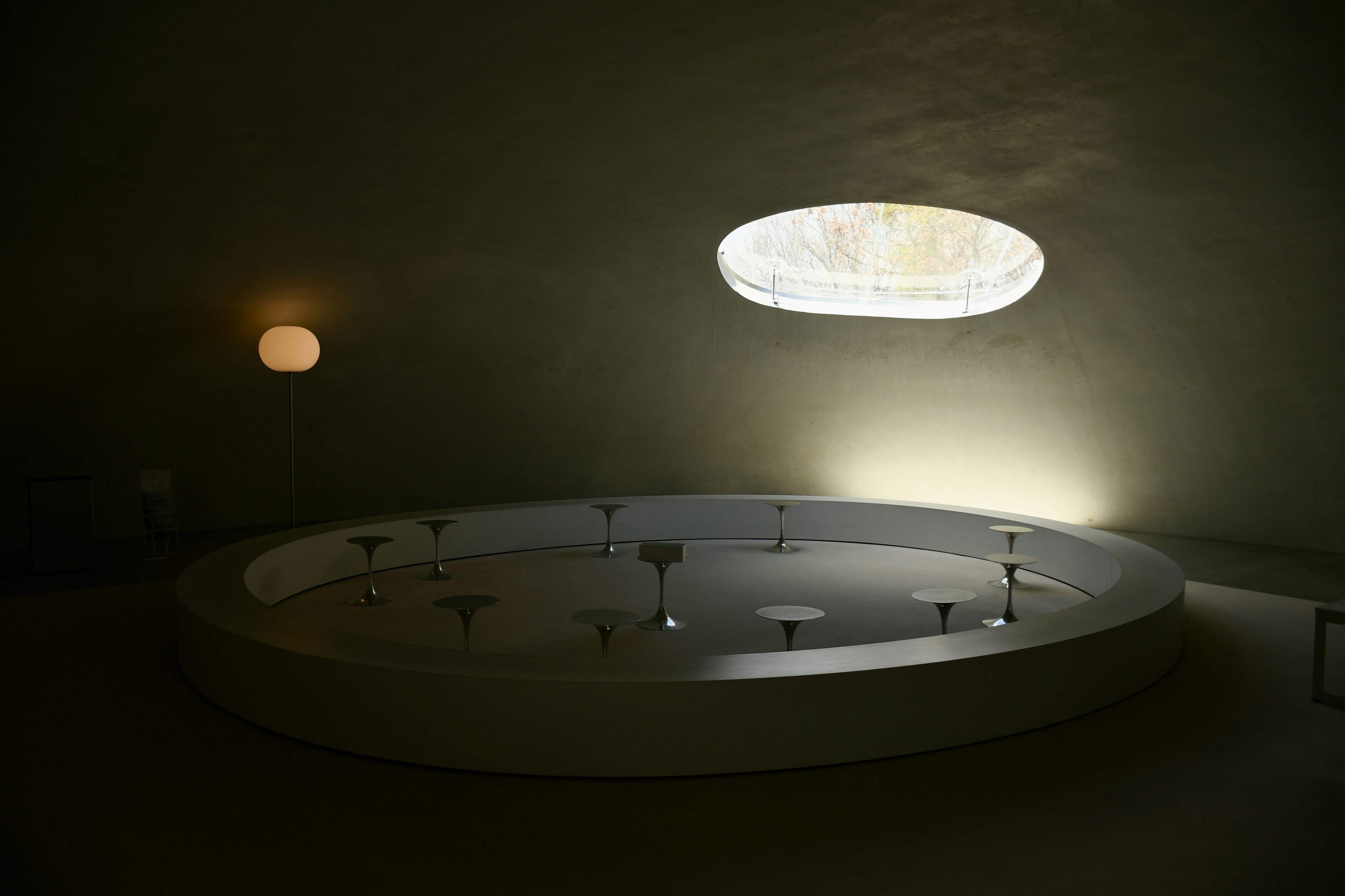 A circular bathtub in a softly lit room with a unique oval window