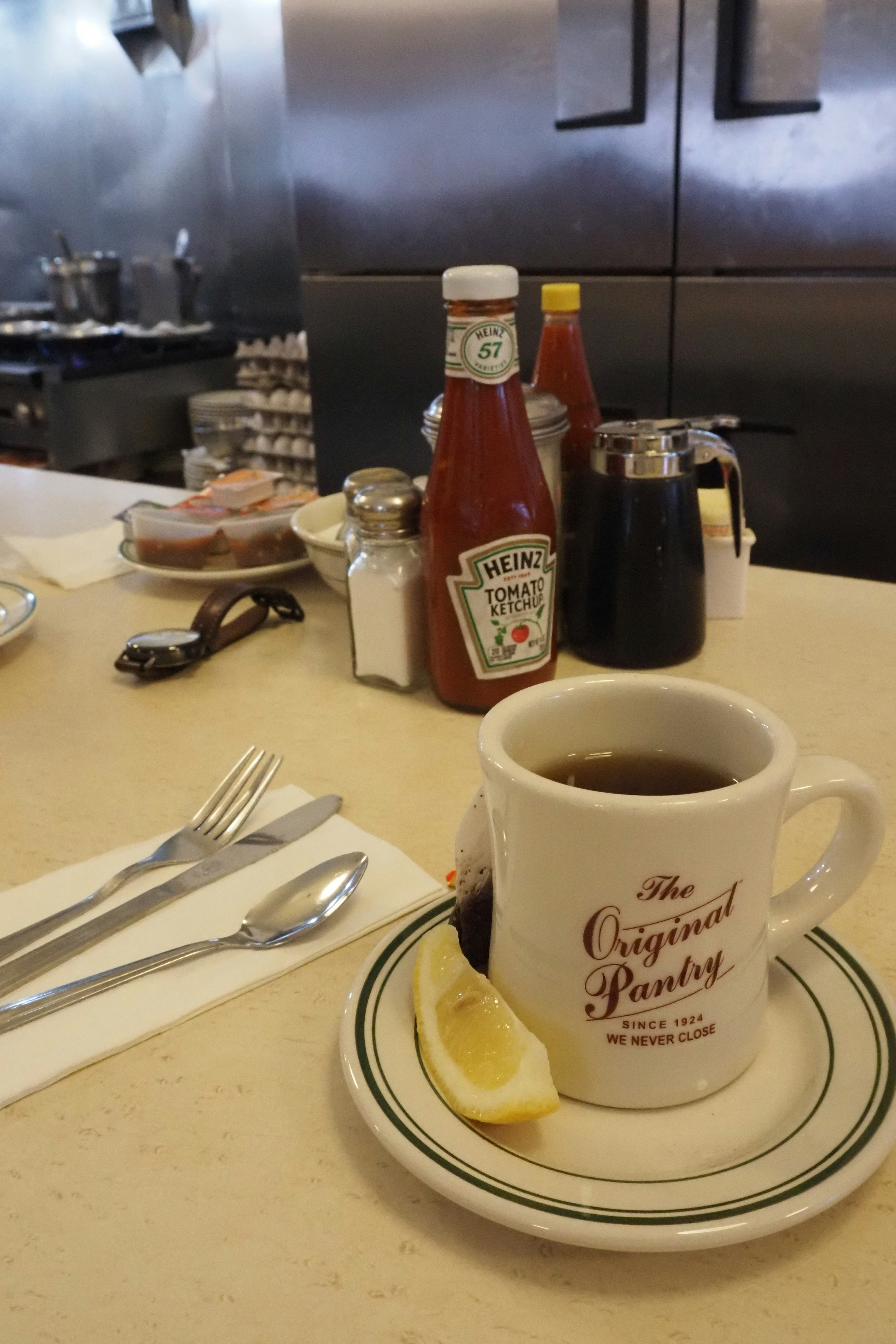 Coffee cup with lemon slice and condiments on a table