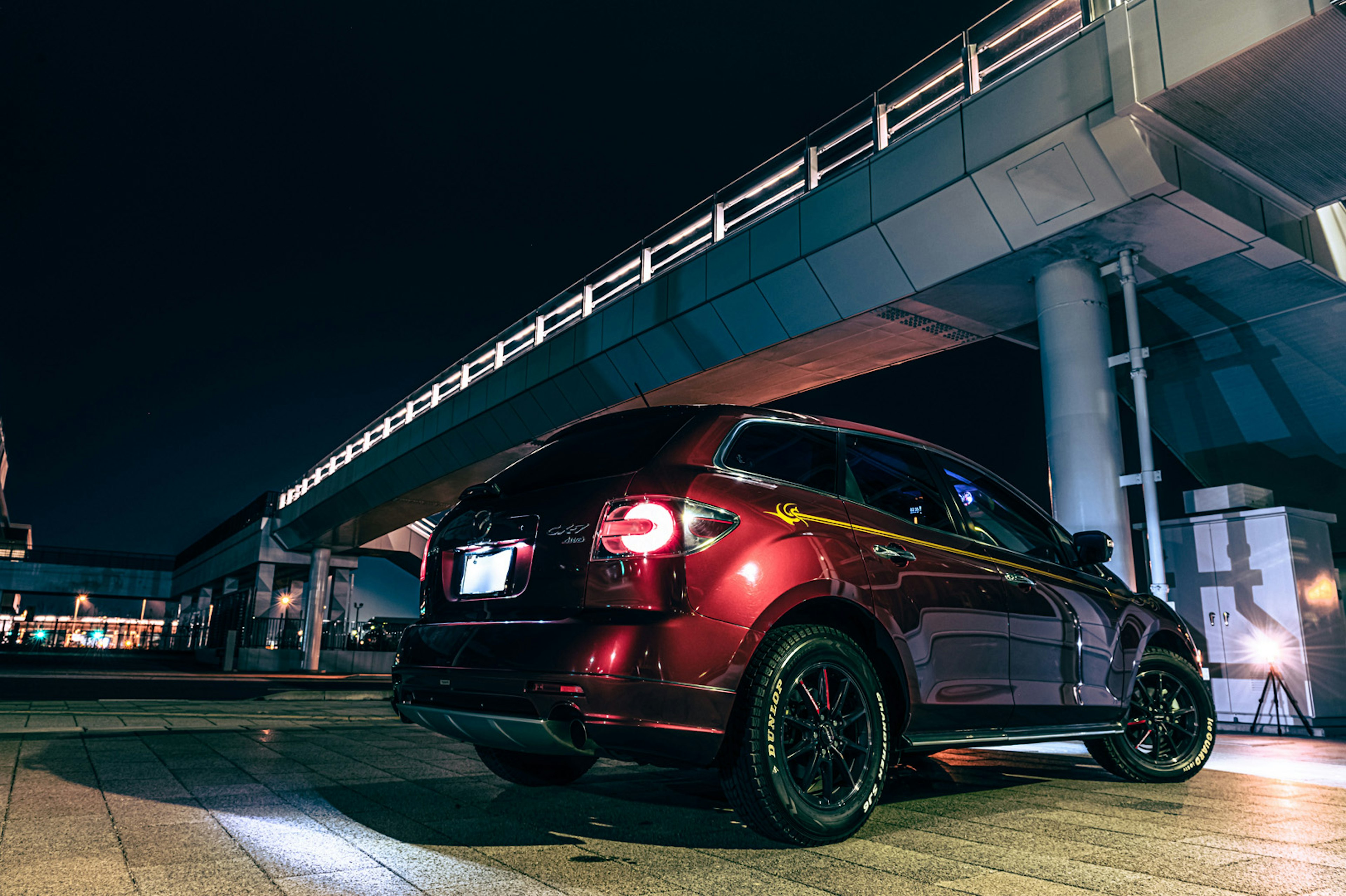 Coche rojo estacionado debajo de un puente por la noche