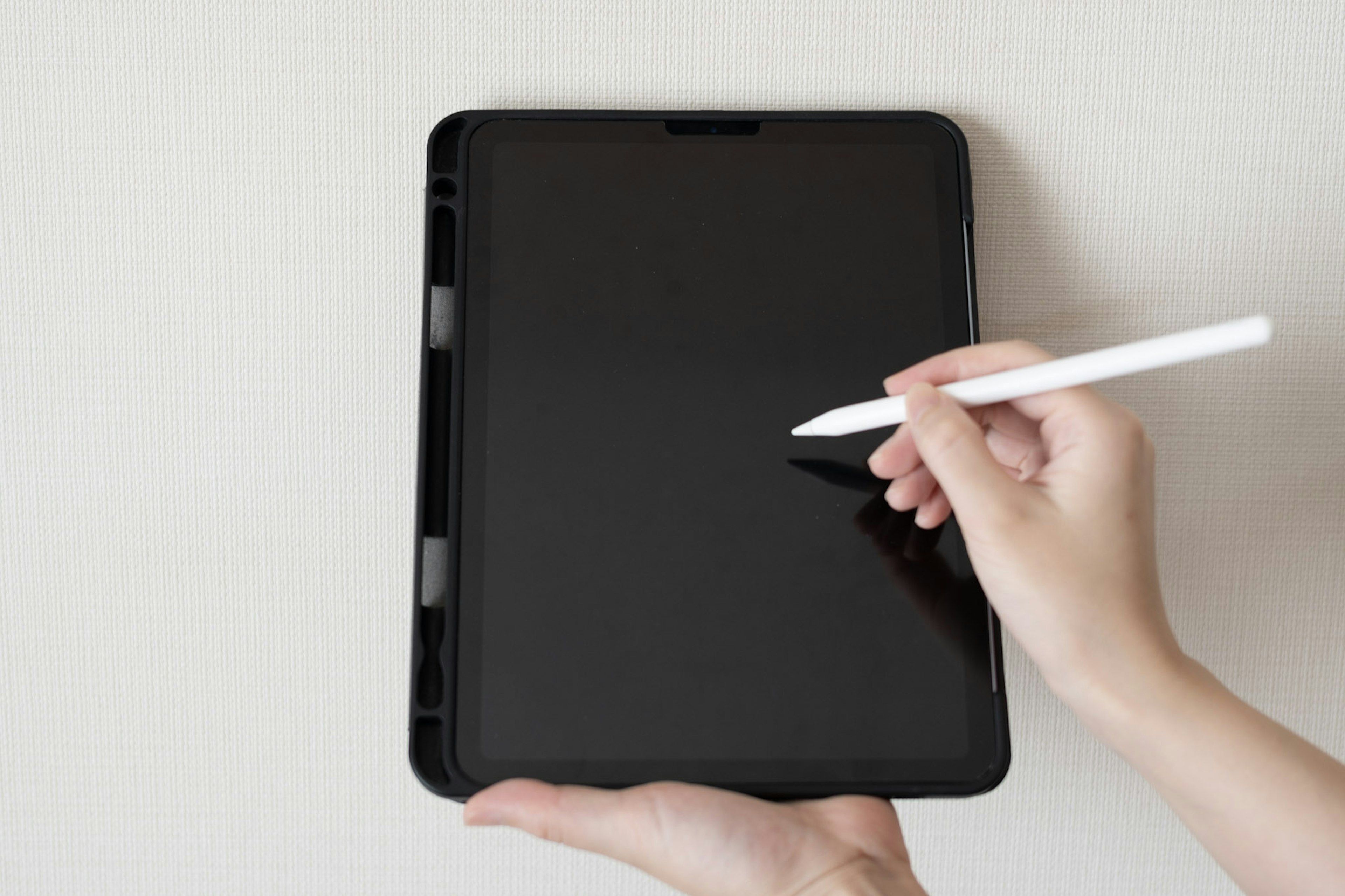 Una mano sosteniendo una tableta con un stylus blanco dibujando en una pantalla en blanco