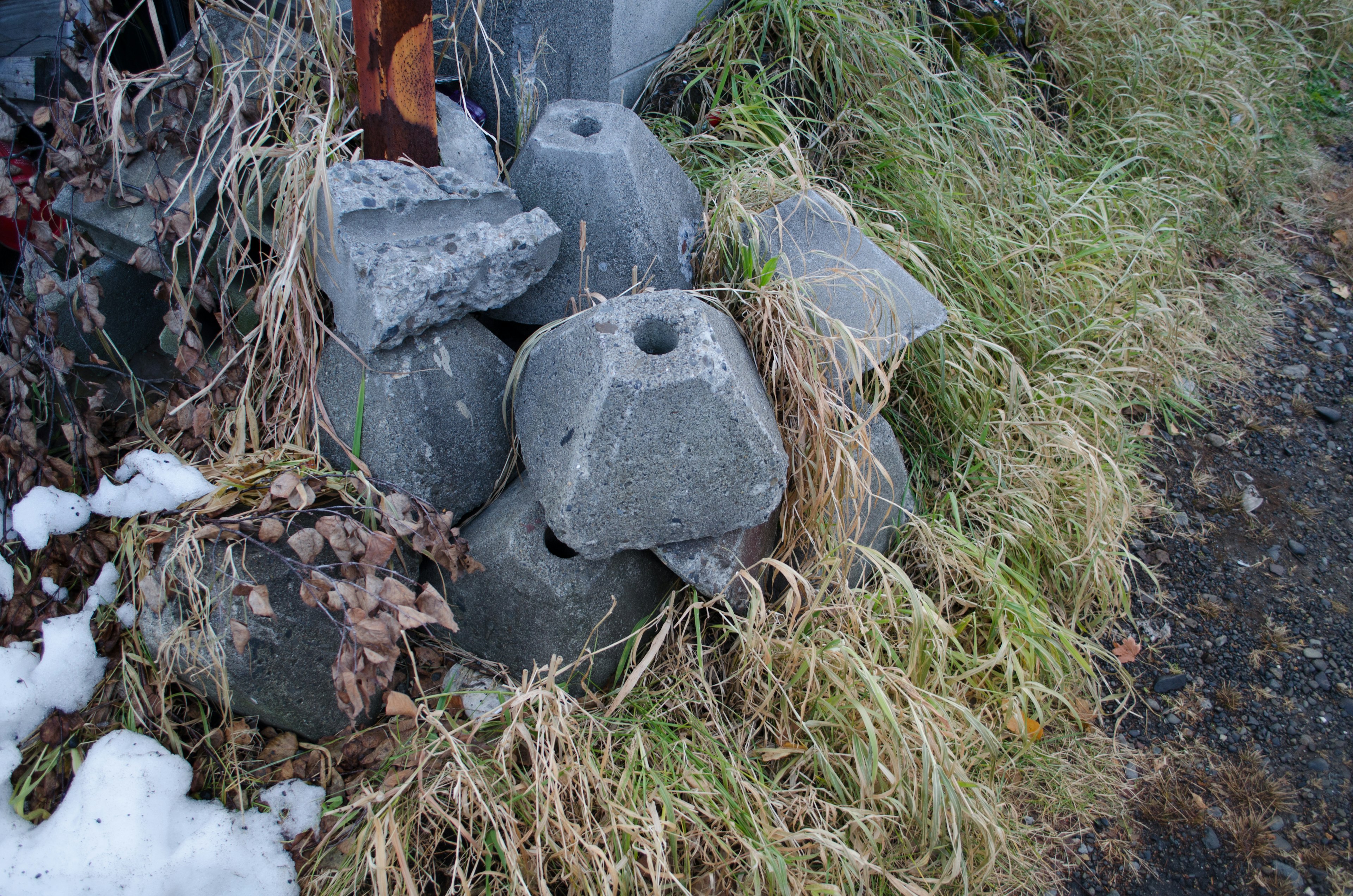 Montón de bloques de piedra gris parcialmente cubiertos de hierba