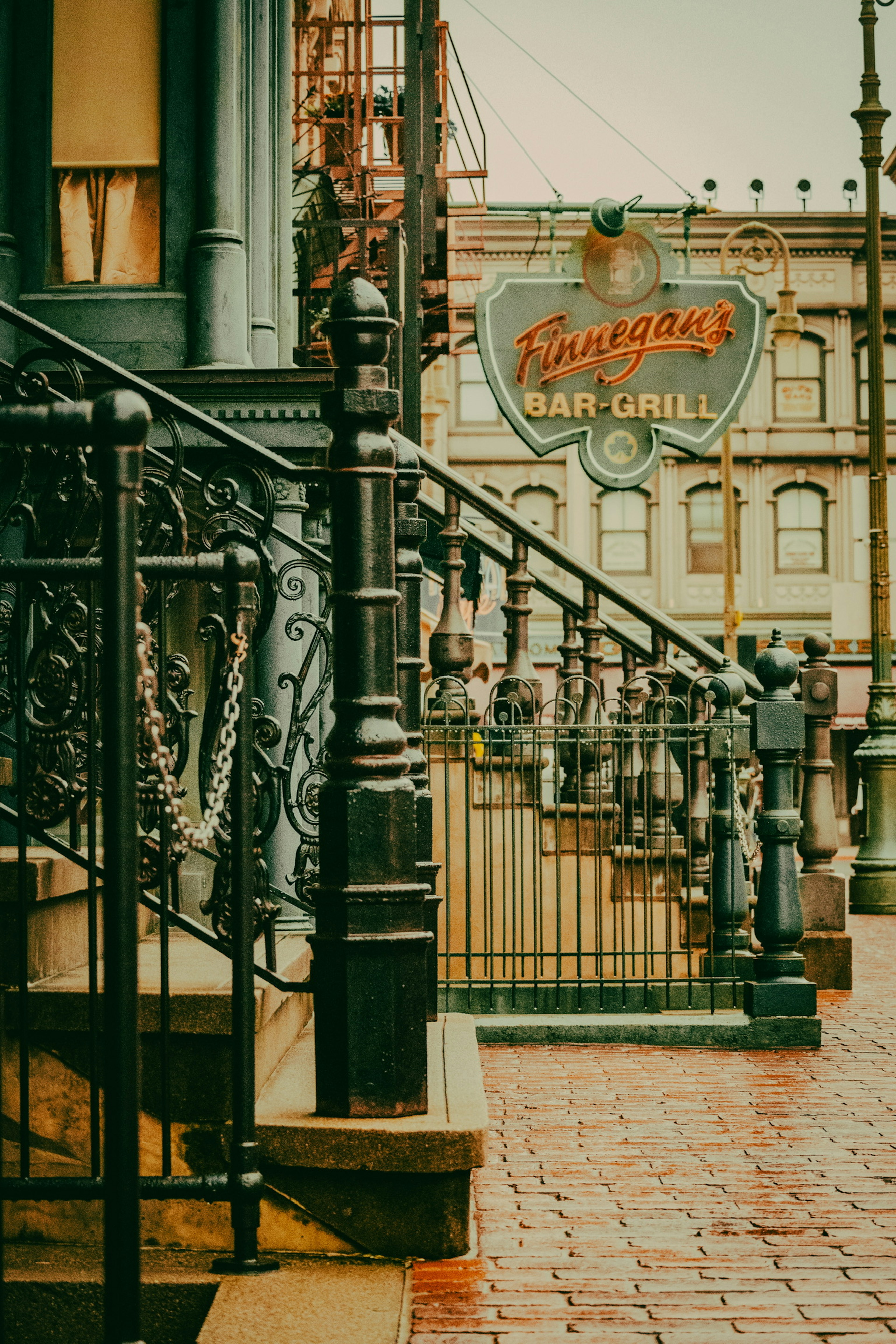 Image of a cafe exterior with iron railing and brick pathway