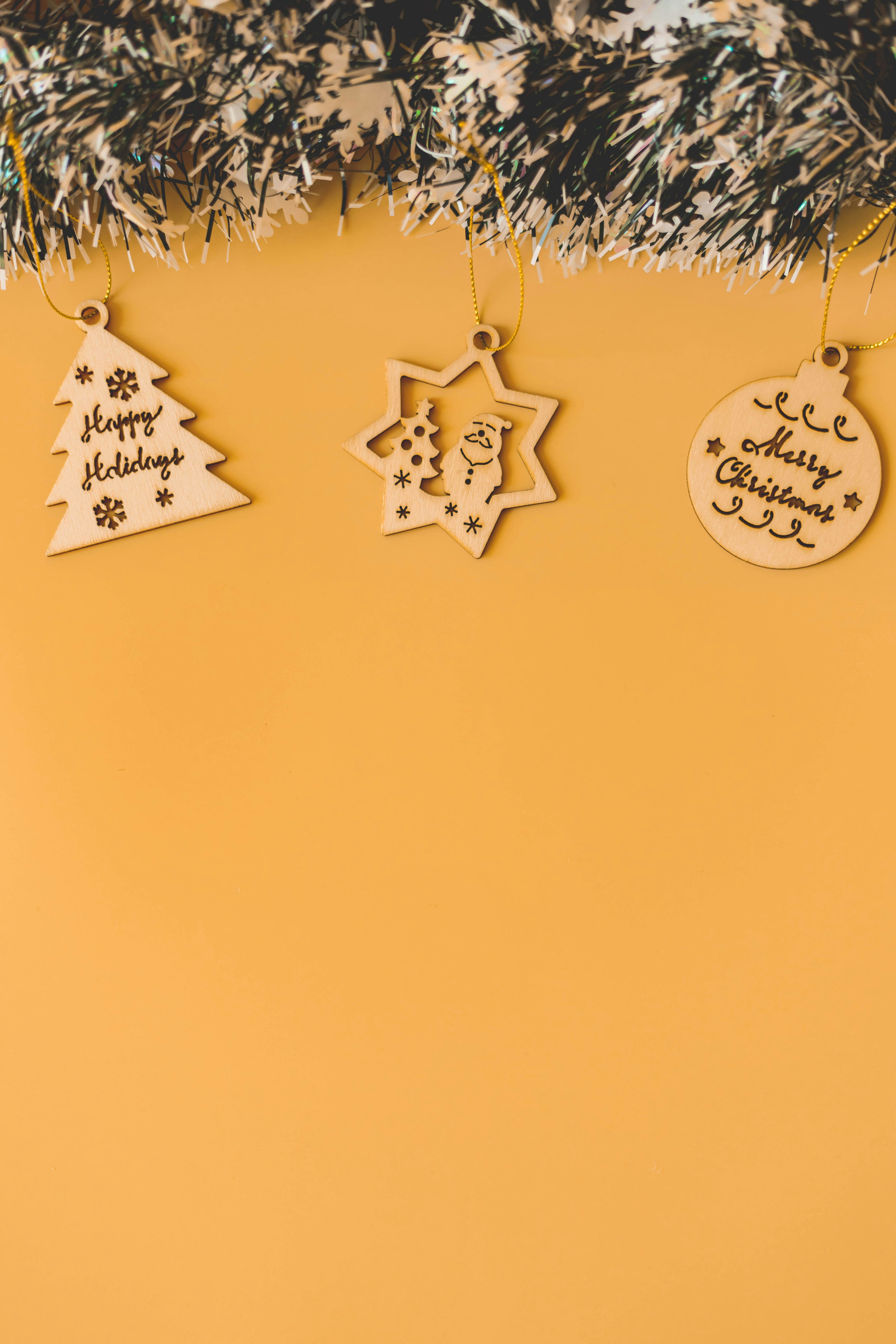 Wooden Christmas ornaments hanging on a yellow background