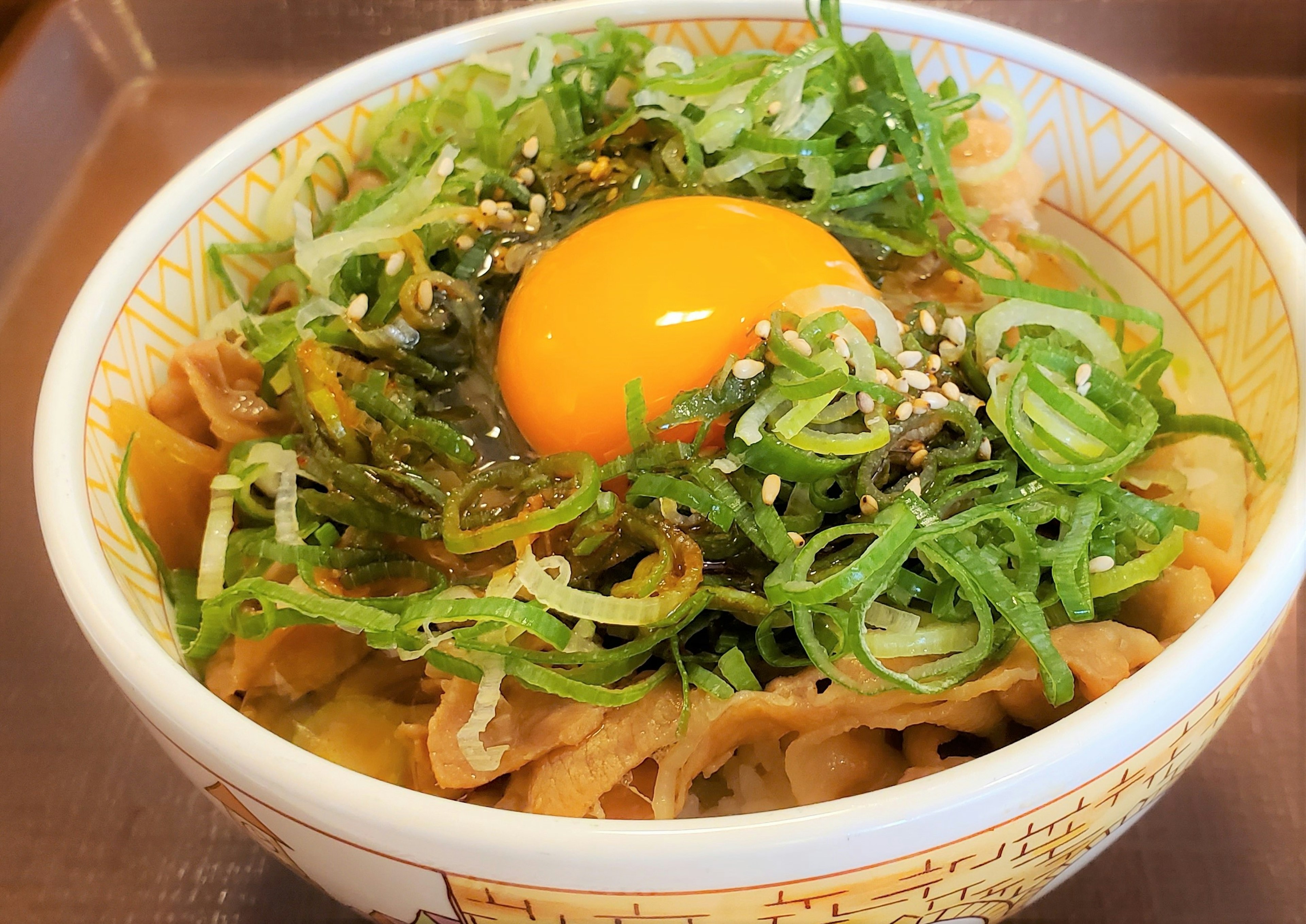 卵黄とネギがトッピングされた豚肉の丼