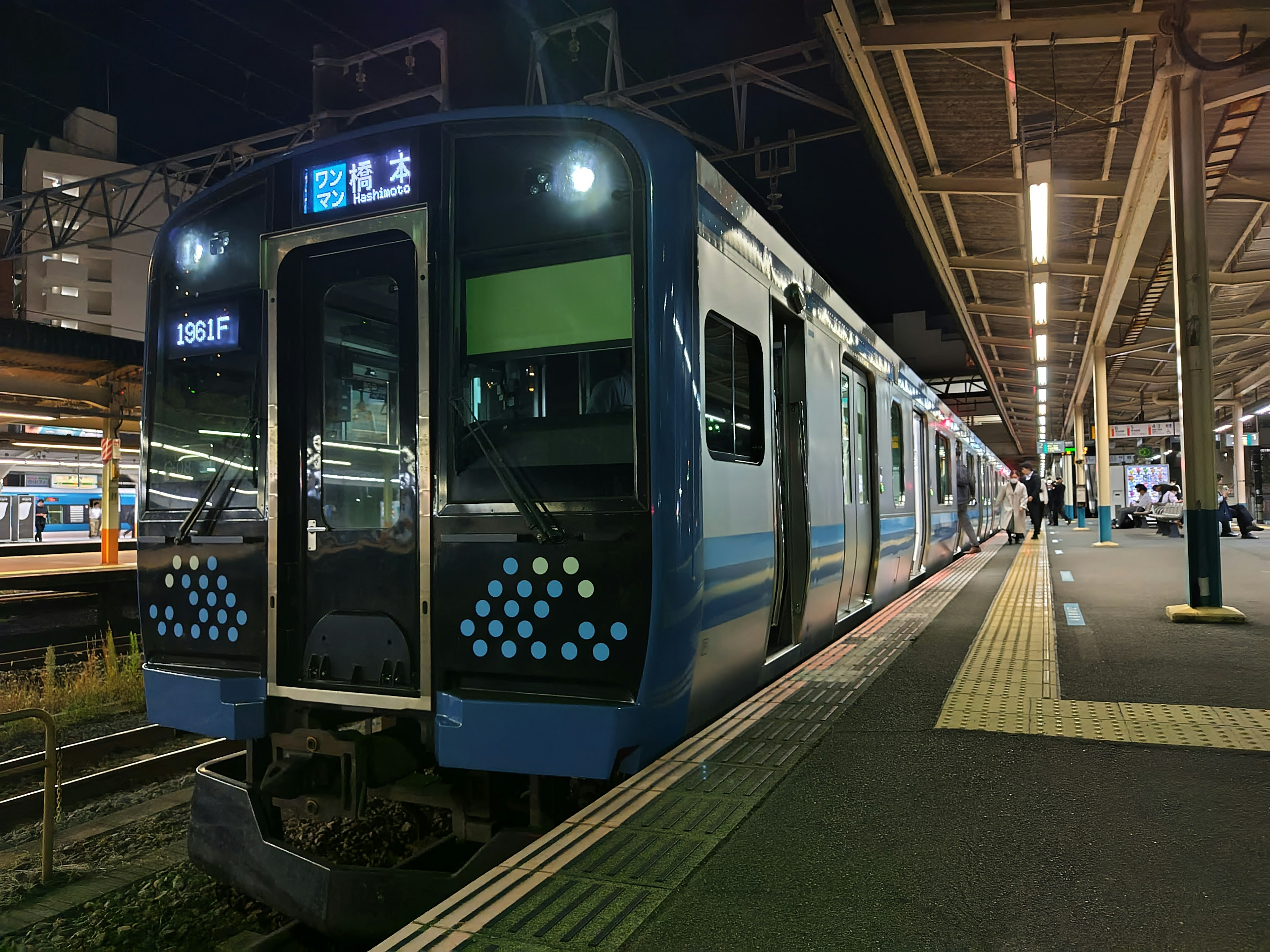 Tren azul detenido en una estación por la noche con luces encendidas