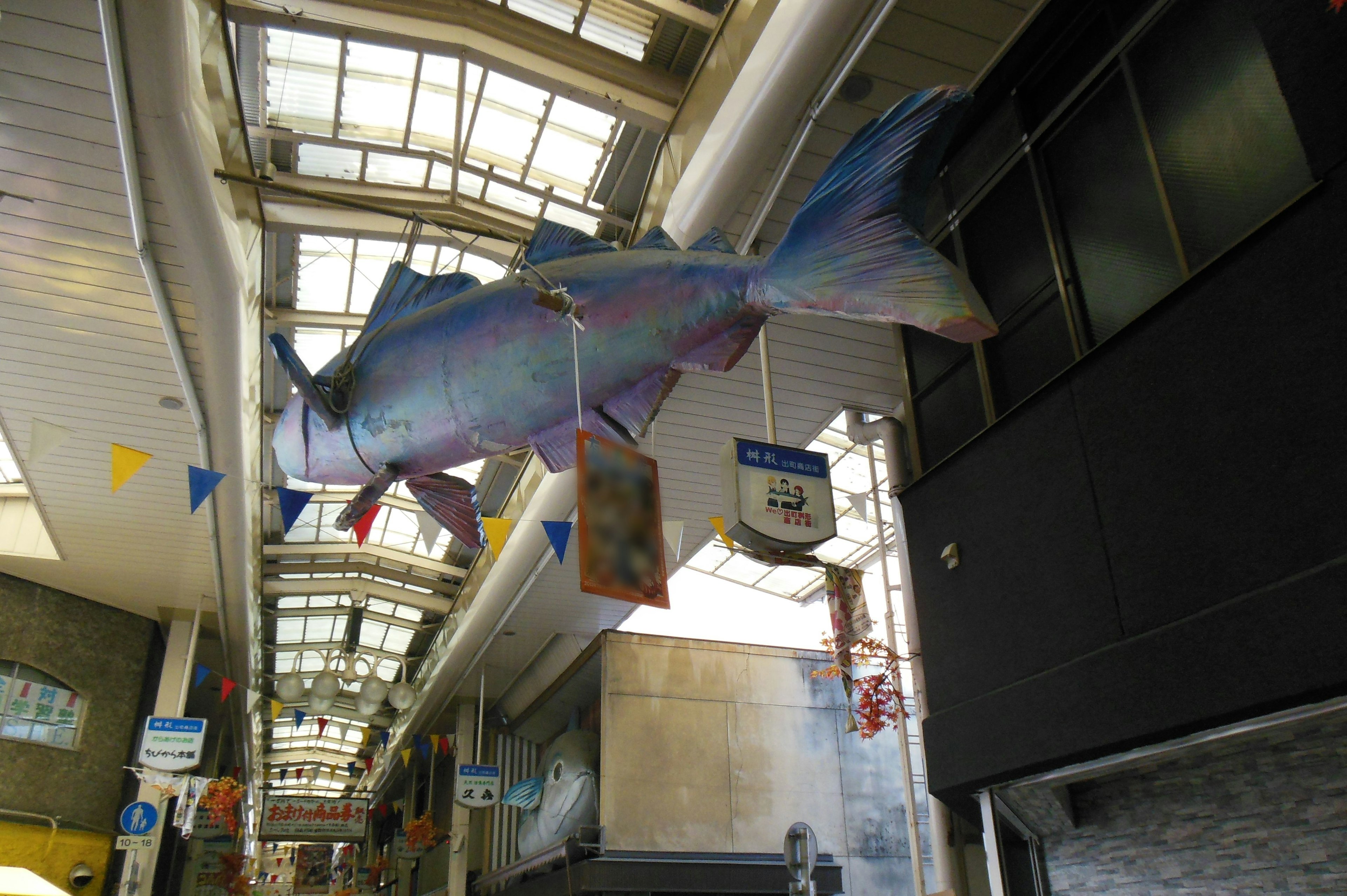 Escultura de pez gigante colgando del techo de un mercado