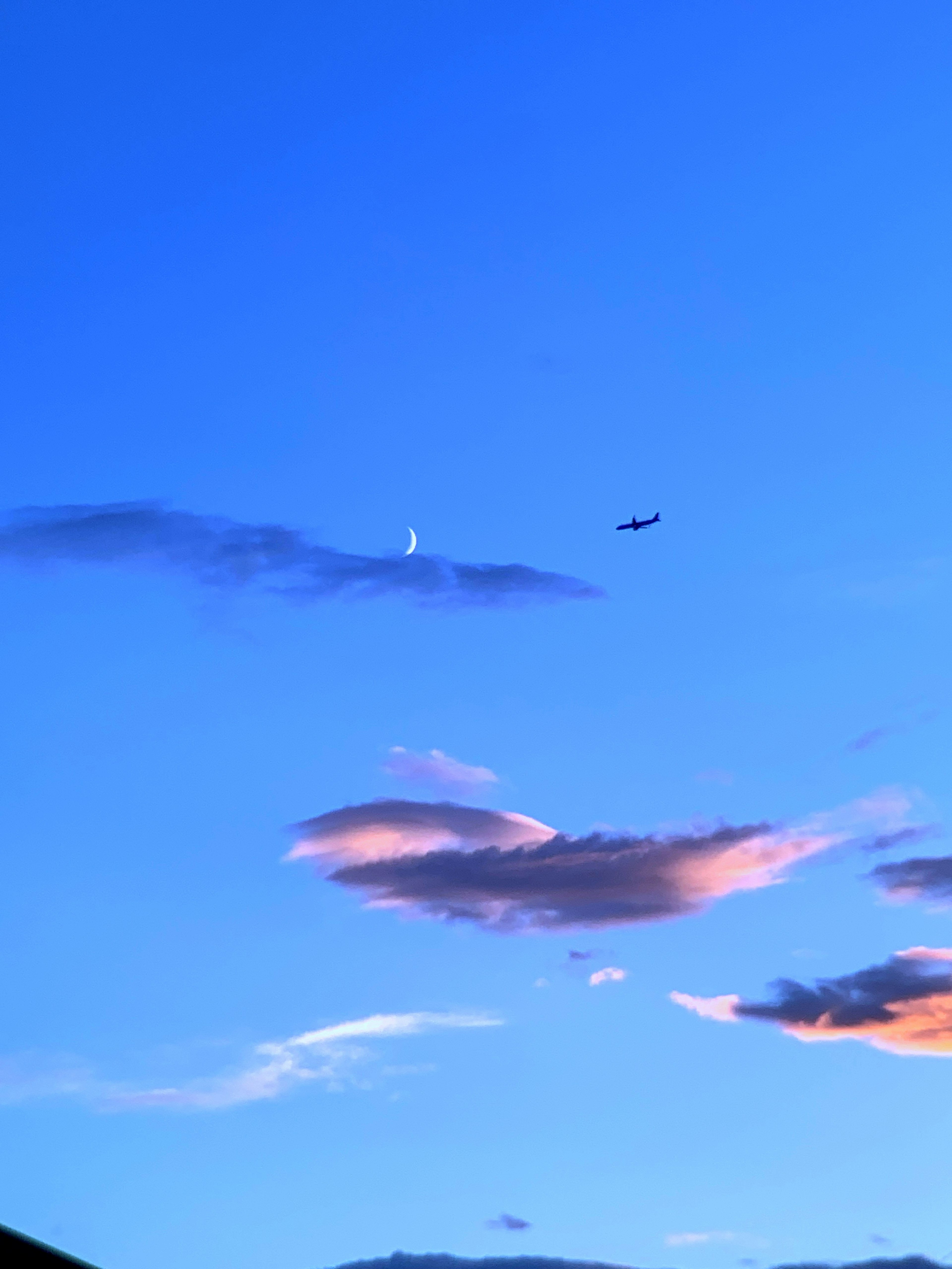 Silhouette eines Flugzeugs vor einem blauen Himmel mit Wolken