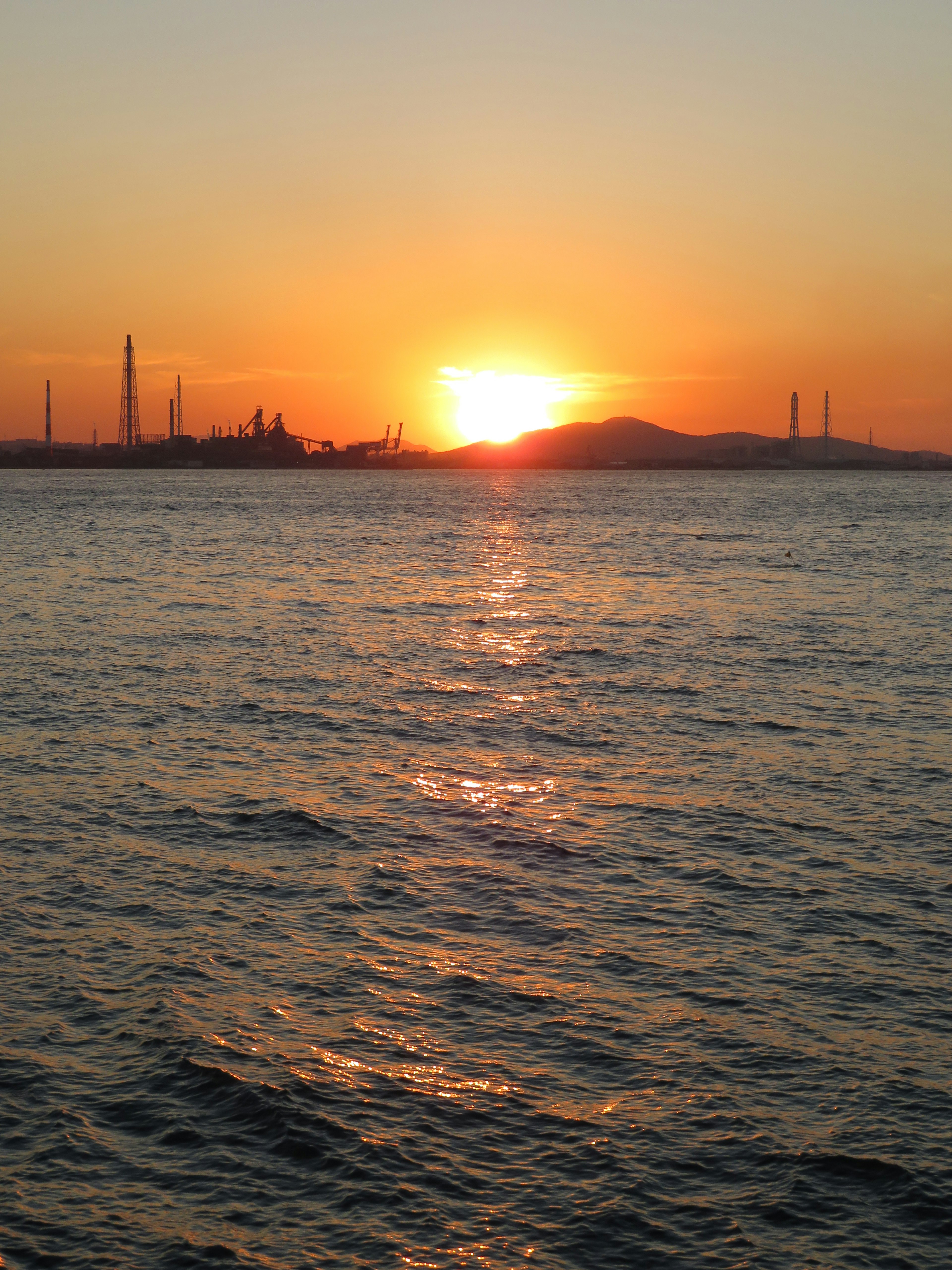 Beautiful sunset over the ocean with silhouette of factories