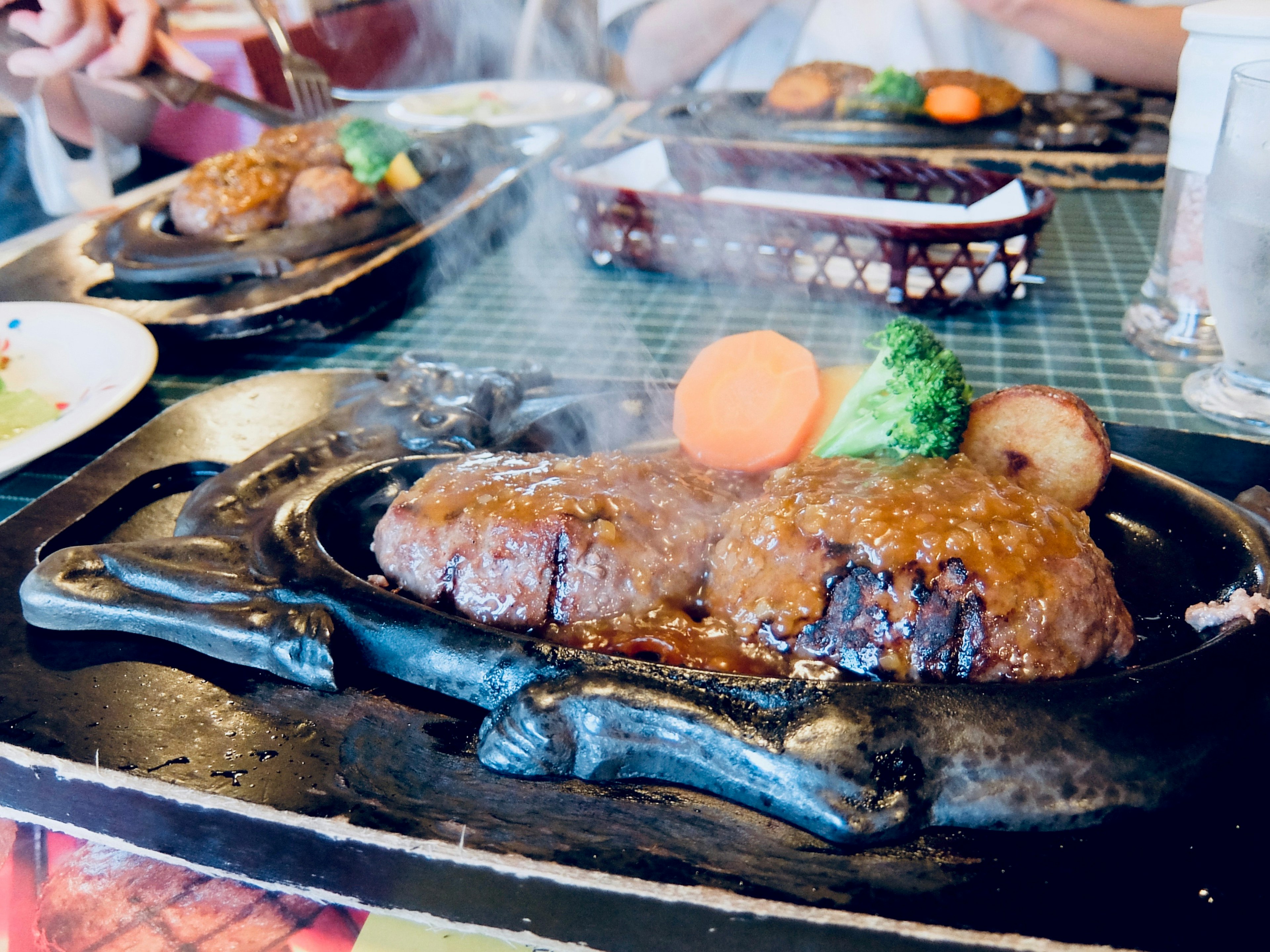 Hamburger steak mendesis di piring panas dengan sayuran