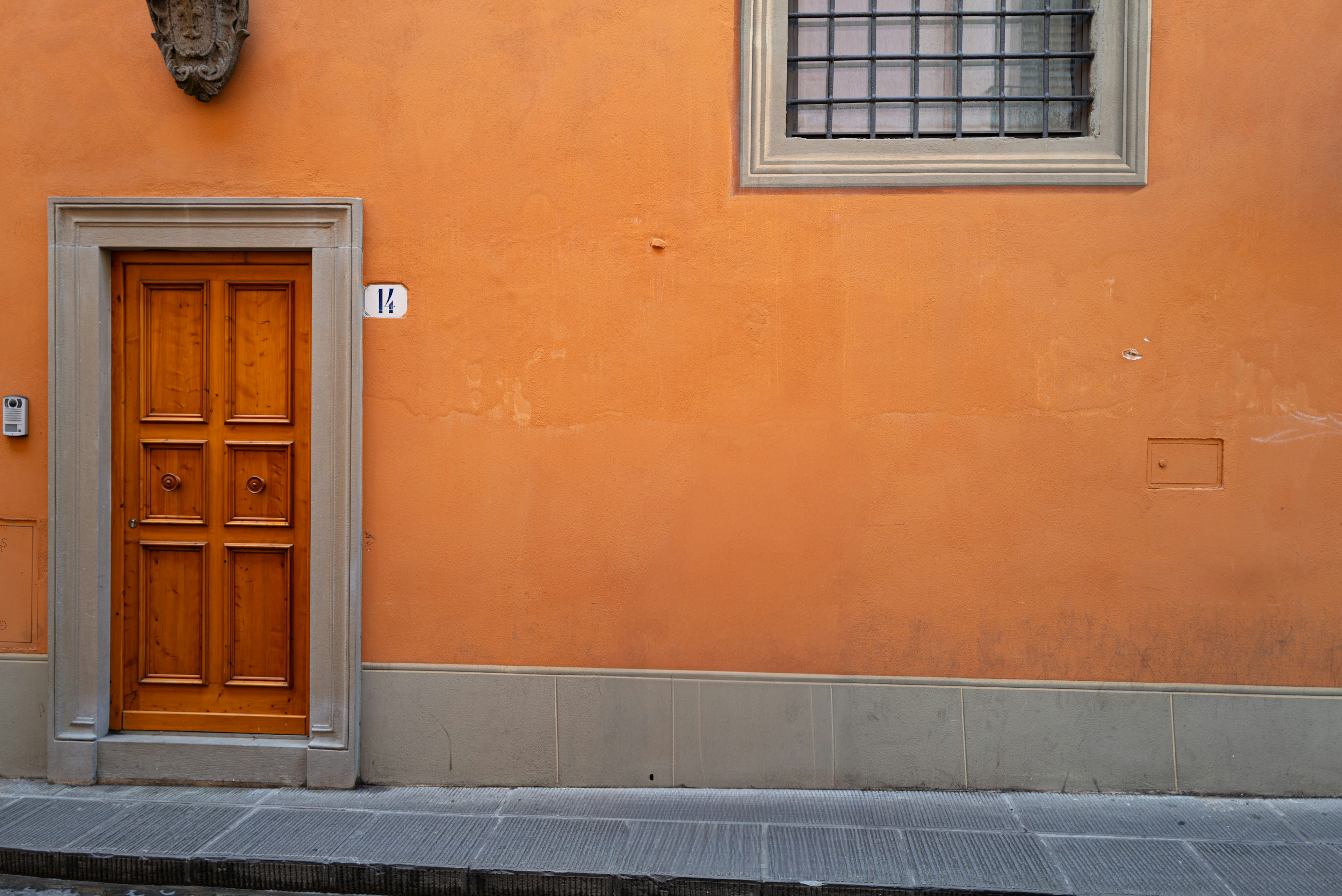 Simple exterior featuring an orange wall with a wooden door and a window