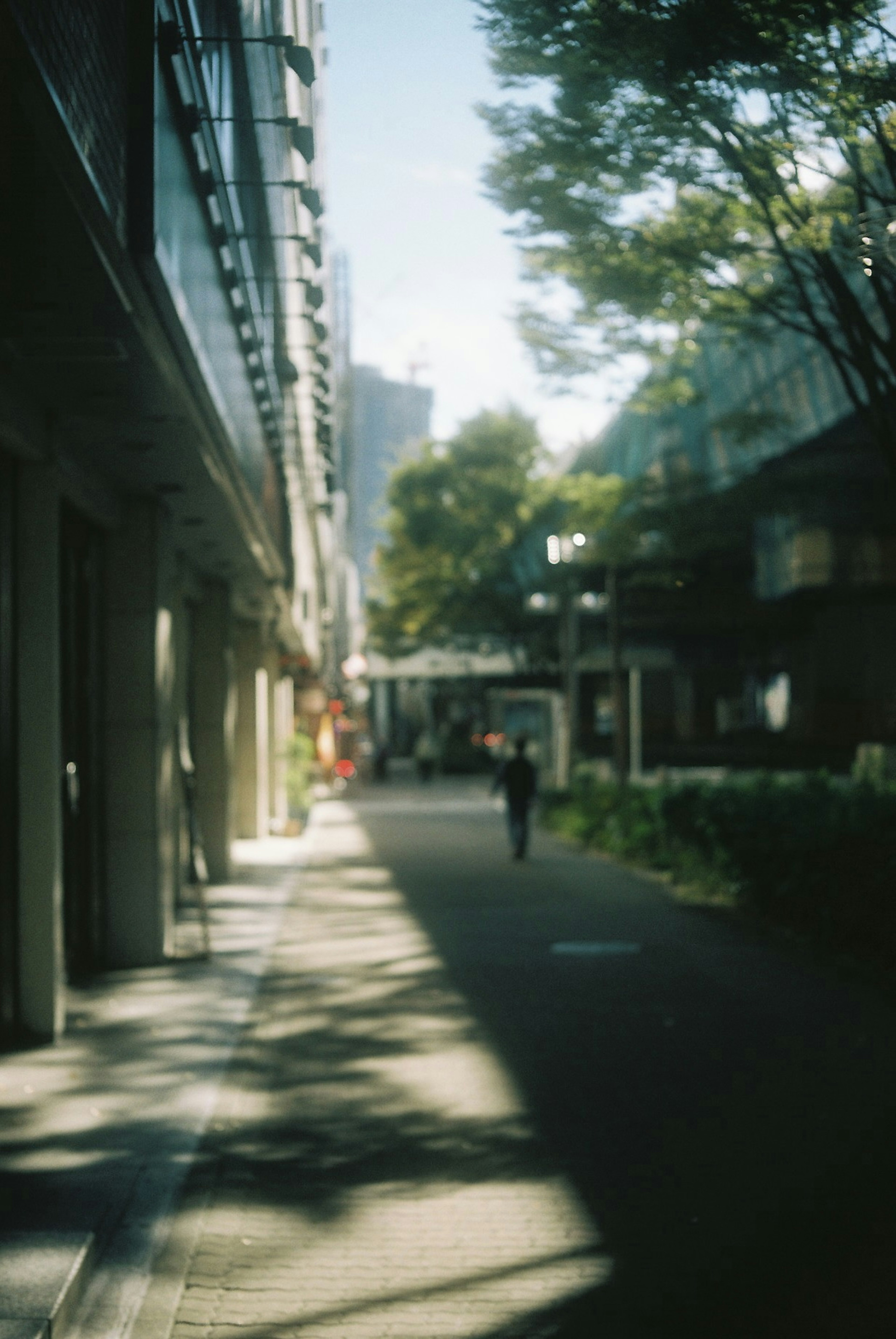 Verschwommene Straßenszene mit schattierten Gebäuden und einer Figur