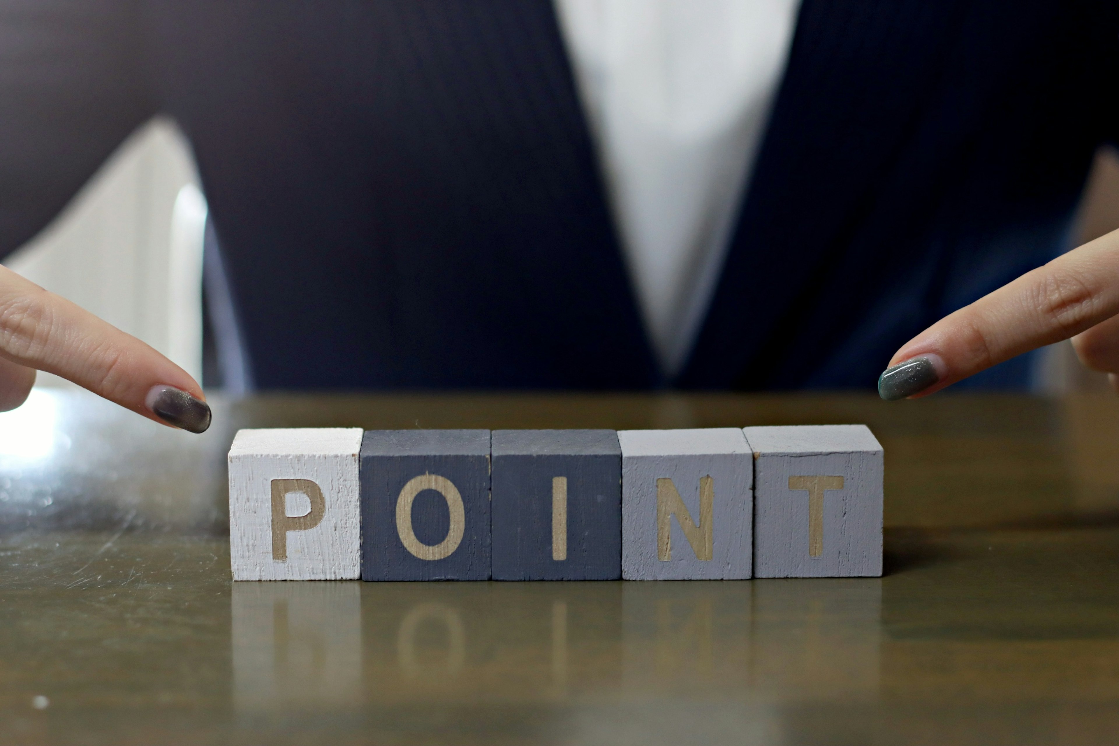 Blocks arranged to spell the word 'POINT' with hands pointing at them