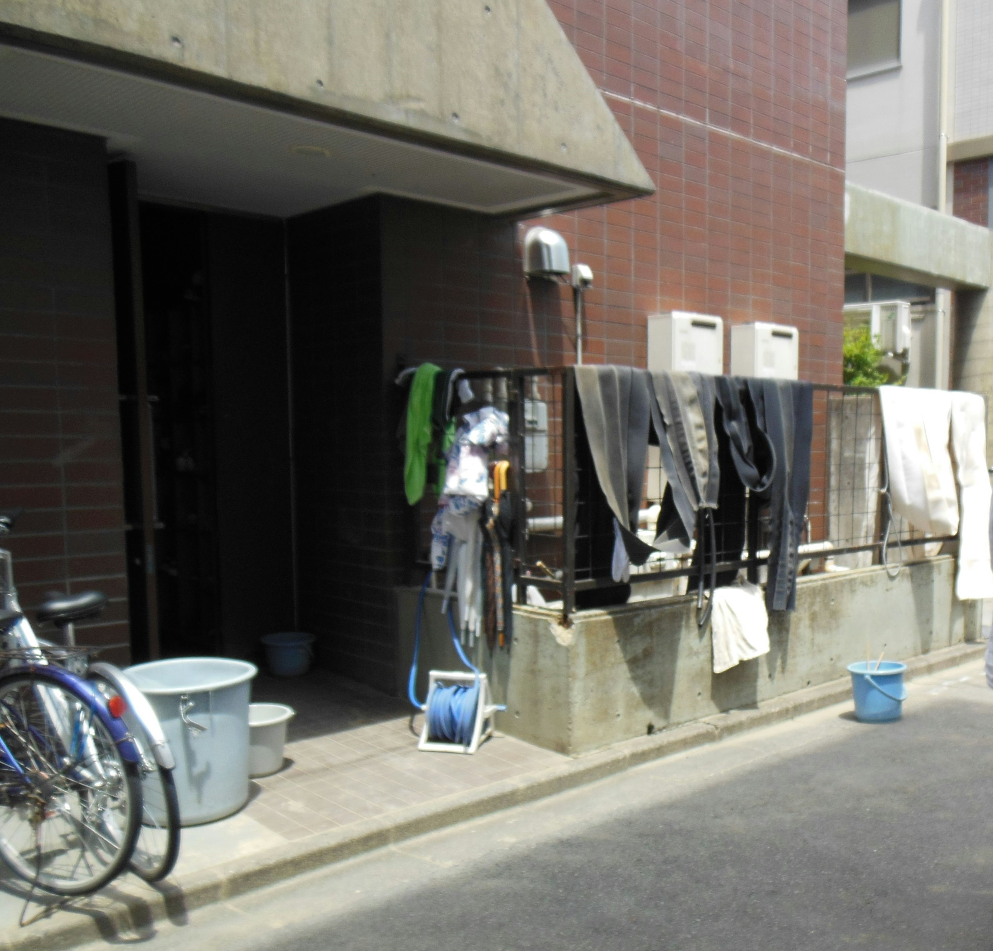 Exterior de un apartamento con ropa colgada bicicletas y cubos visibles