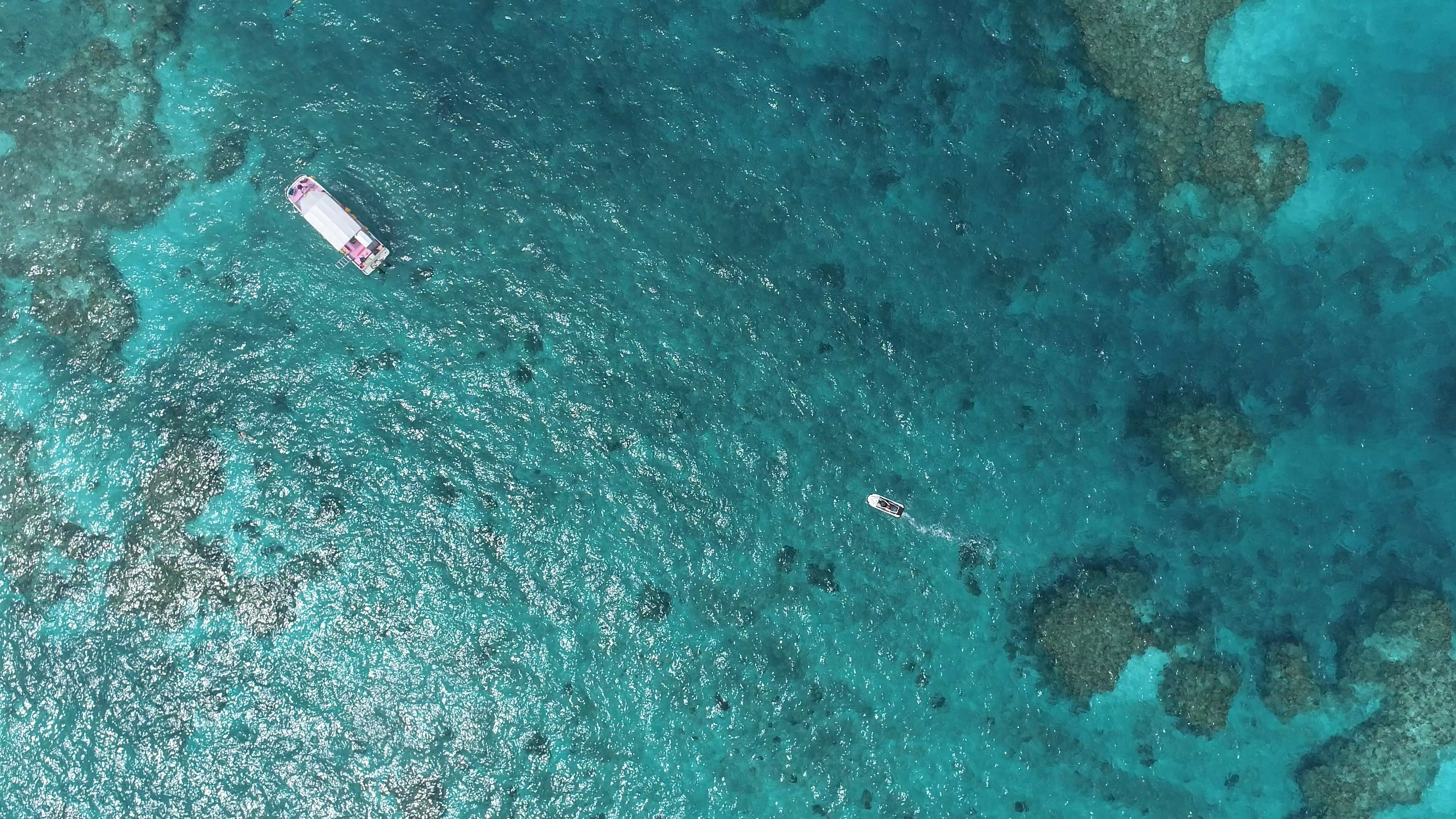 Aerial view of boats on a turquoise sea with coral reefs visible