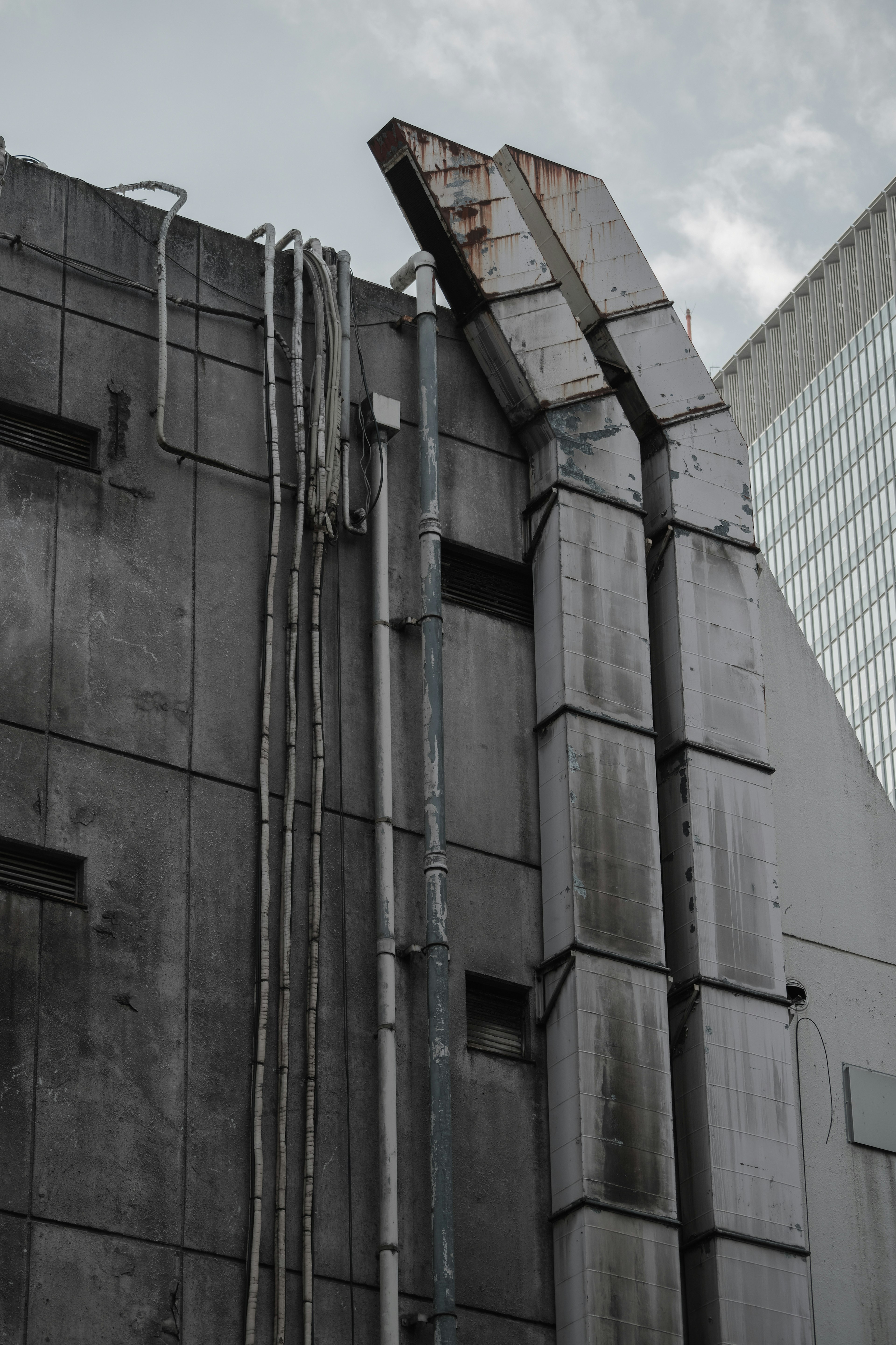 Parete in cemento grigio con tubi e caratteristiche metalliche arrugginite