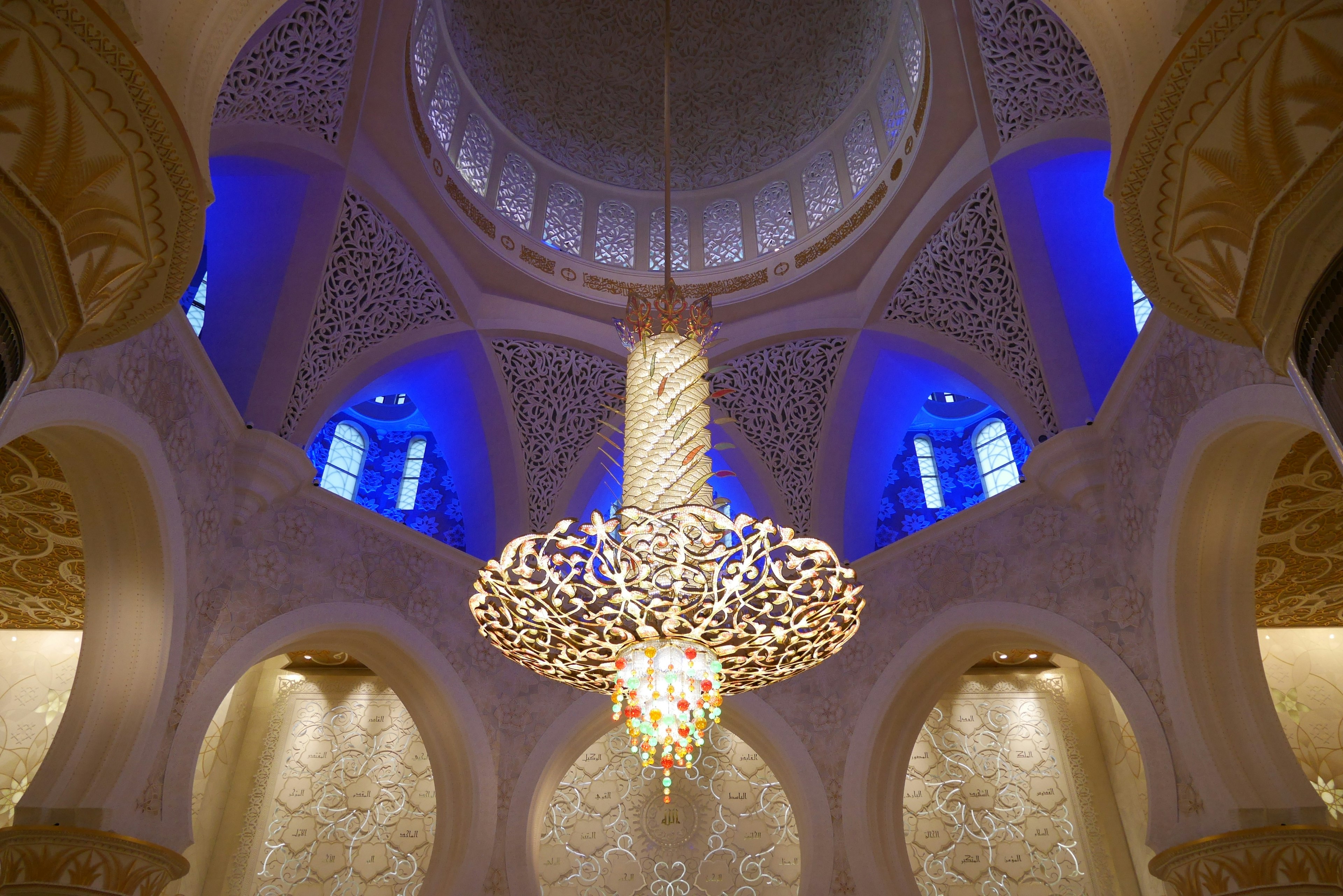 Interior de una mezquita con un impresionante candelabro y luces azules decorativas