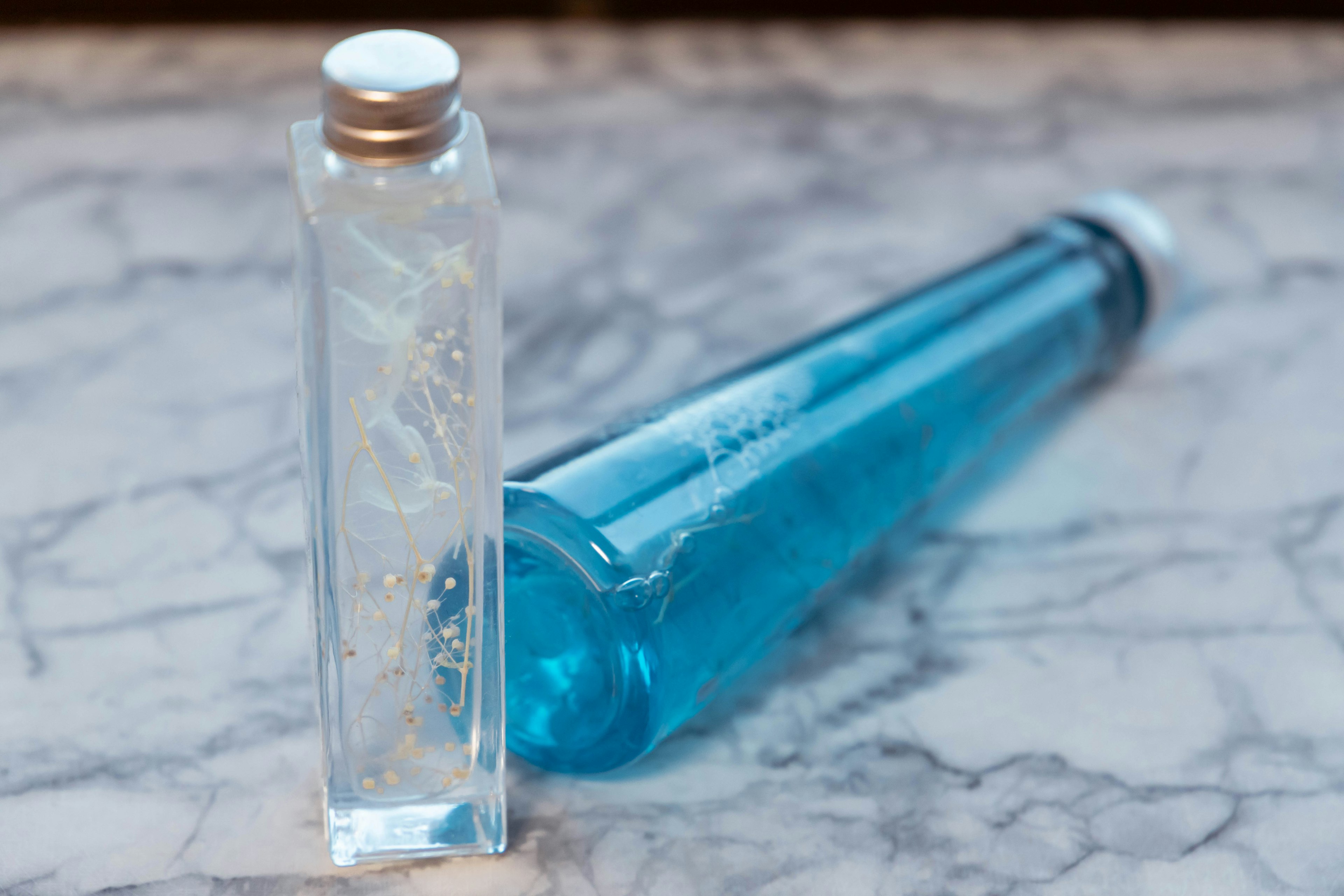 A blue bottle and a clear bottle placed on a marble surface