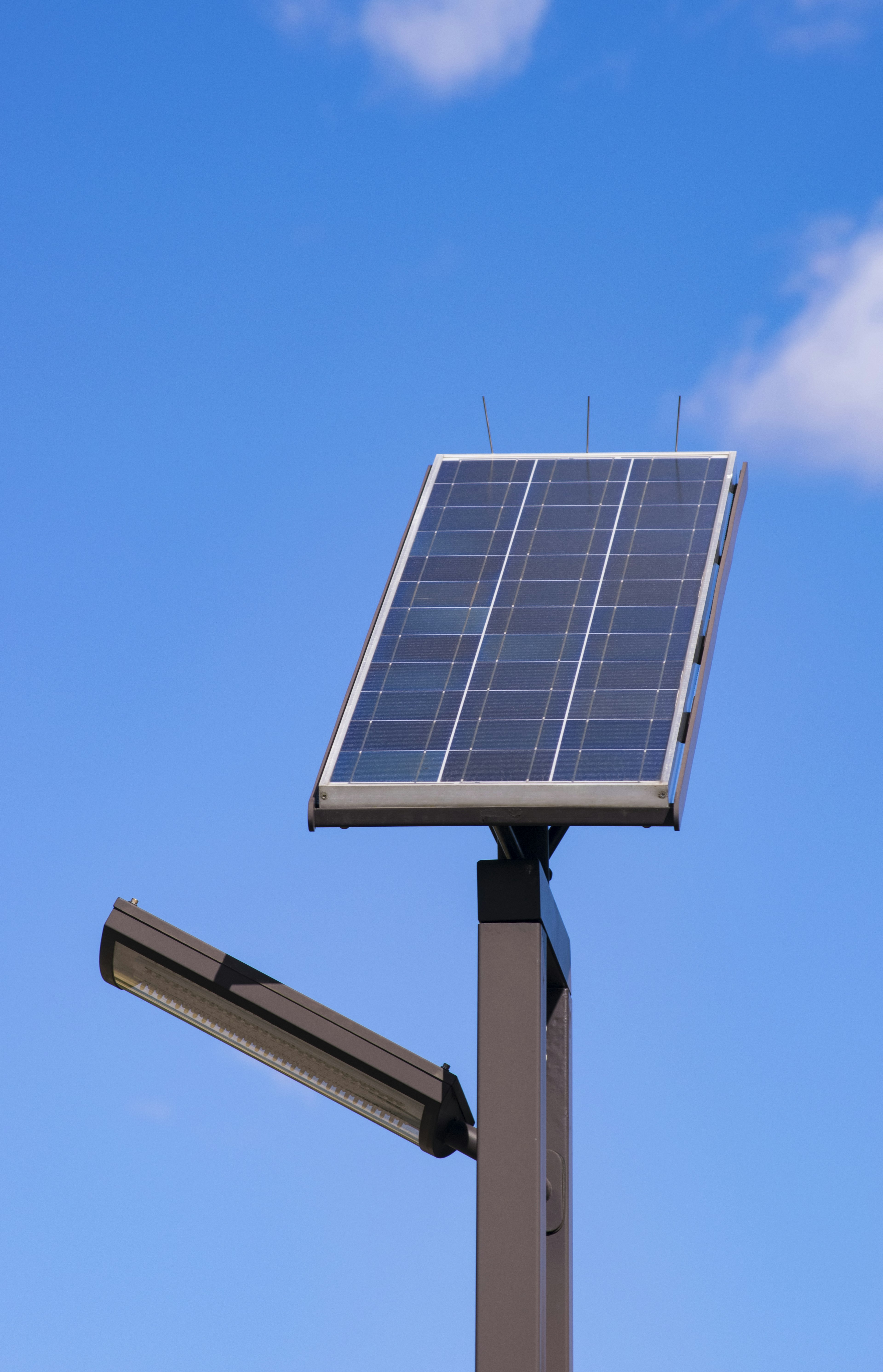 Panneau solaire monté sur un poteau avec un lampadaire sous un ciel bleu