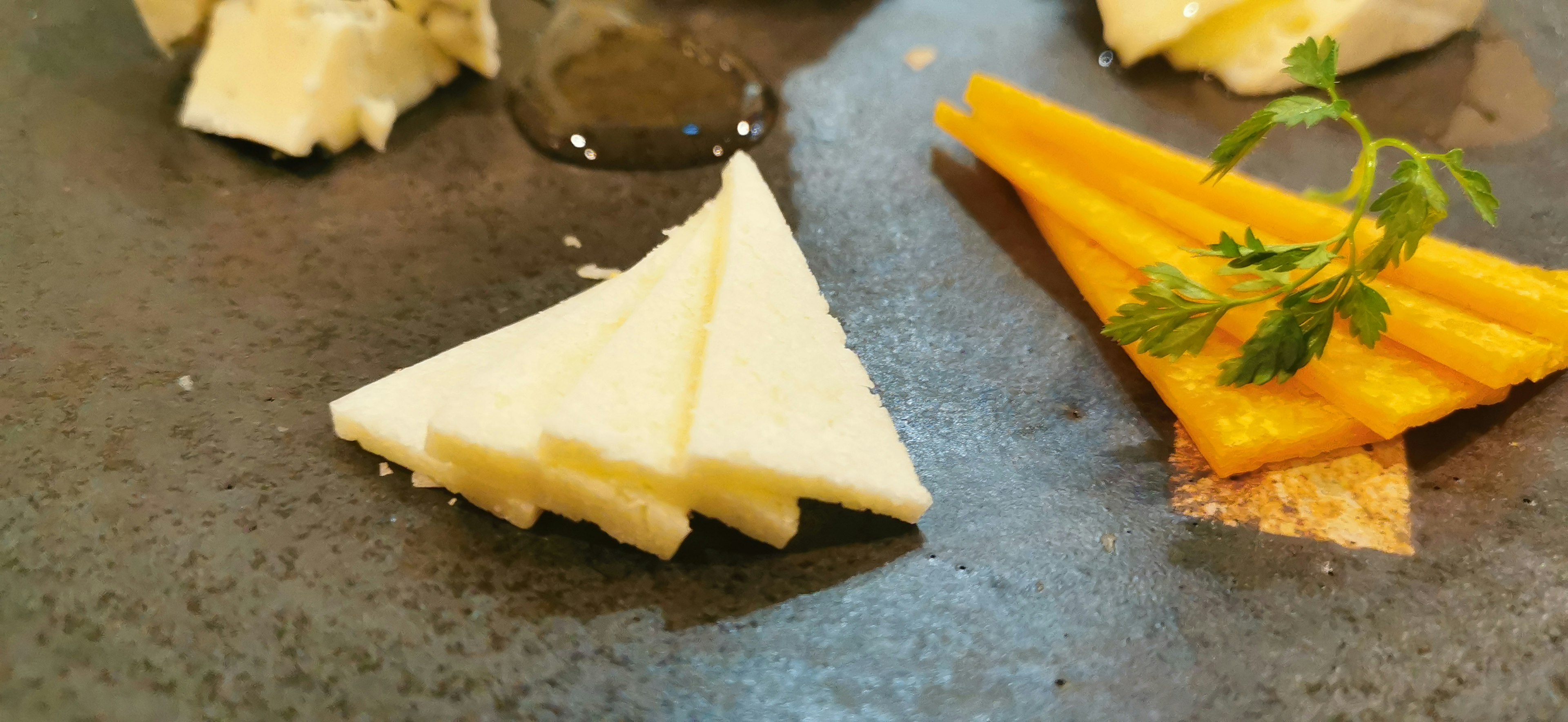 Disposizione di formaggio triangolare e verdure arancioni su un piatto