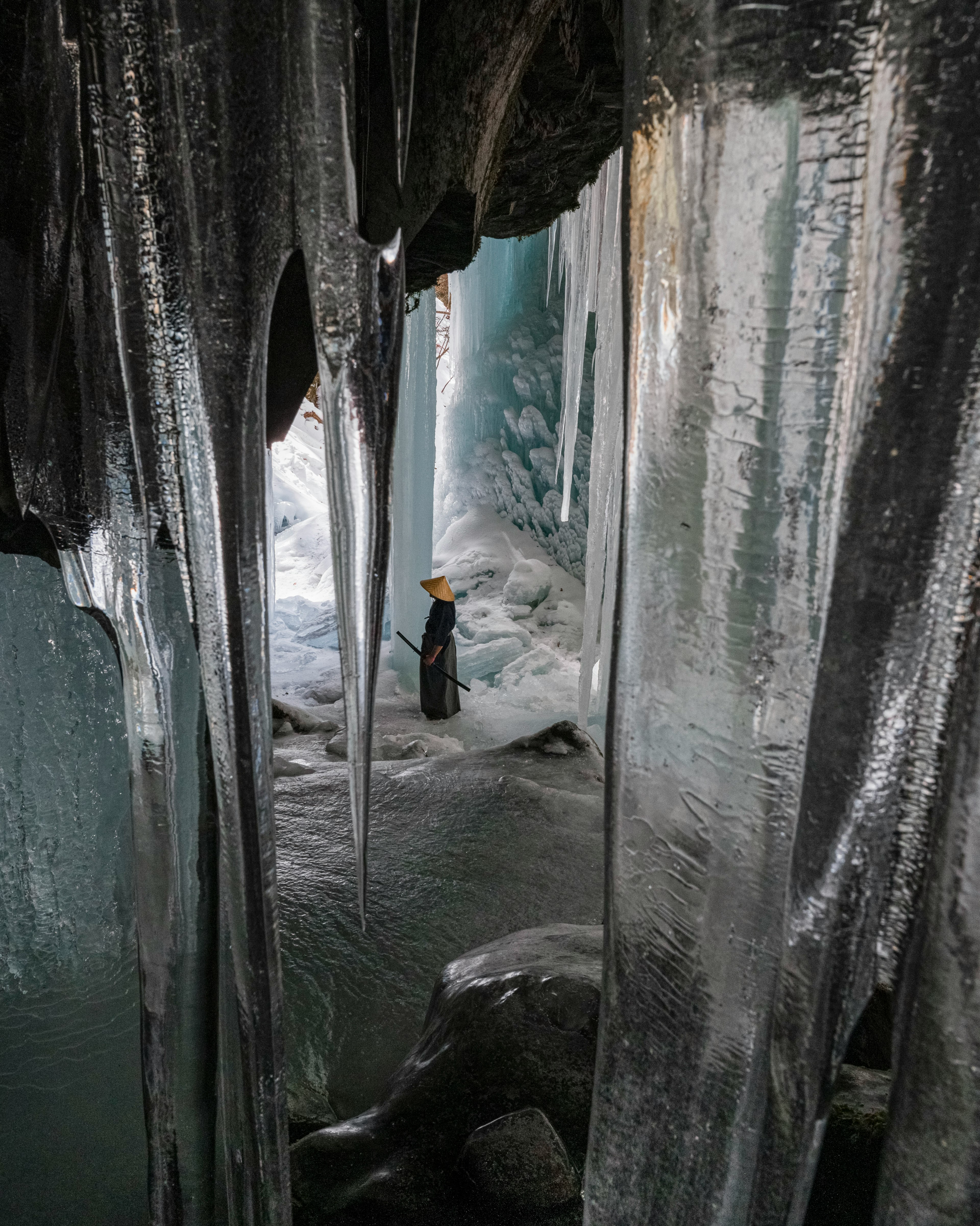 Una persona de pie dentro de una cueva de hielo con impresionantes columnas de hielo y paredes de hielo azul