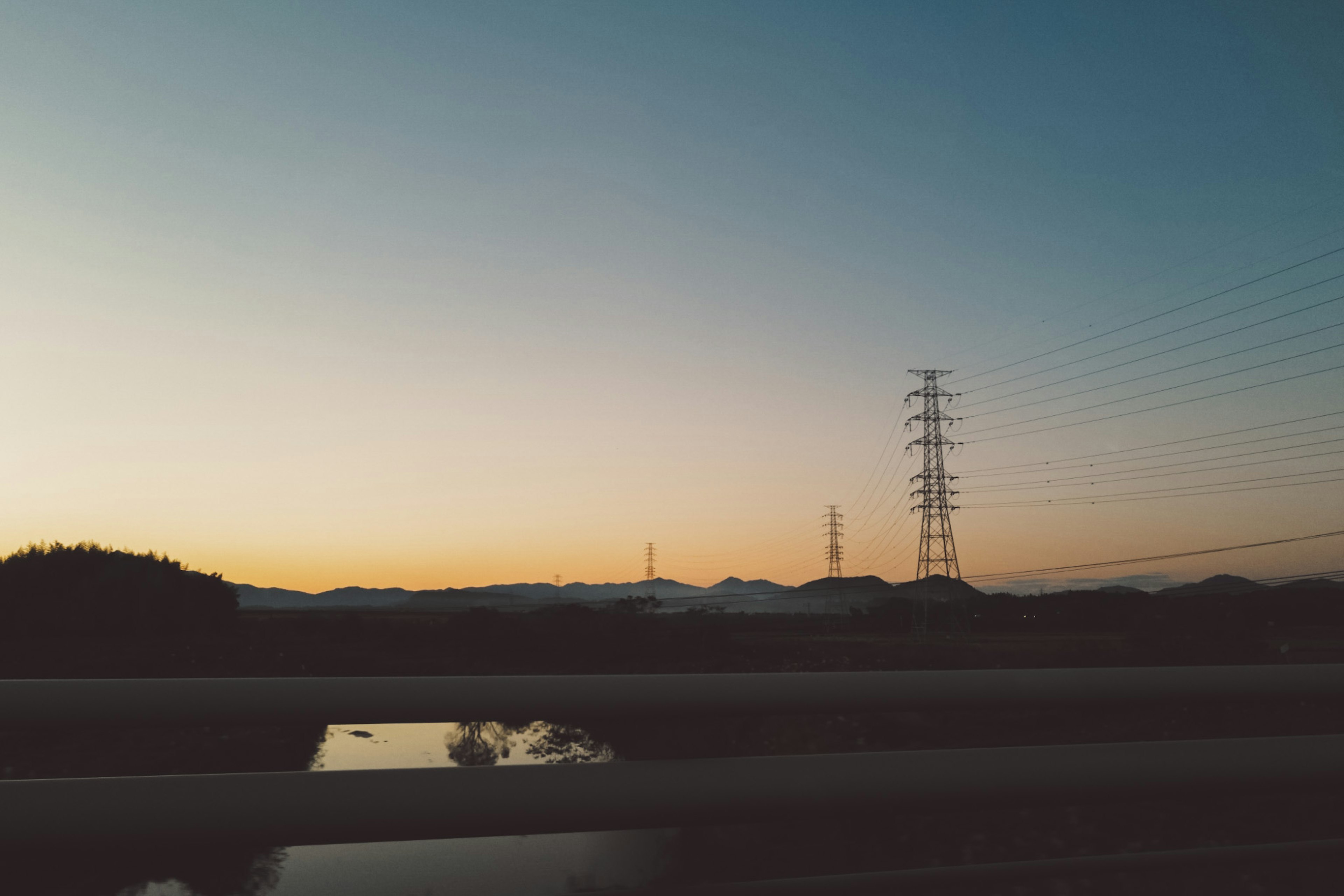 夕暮れ時の山々と電柱が映る風景